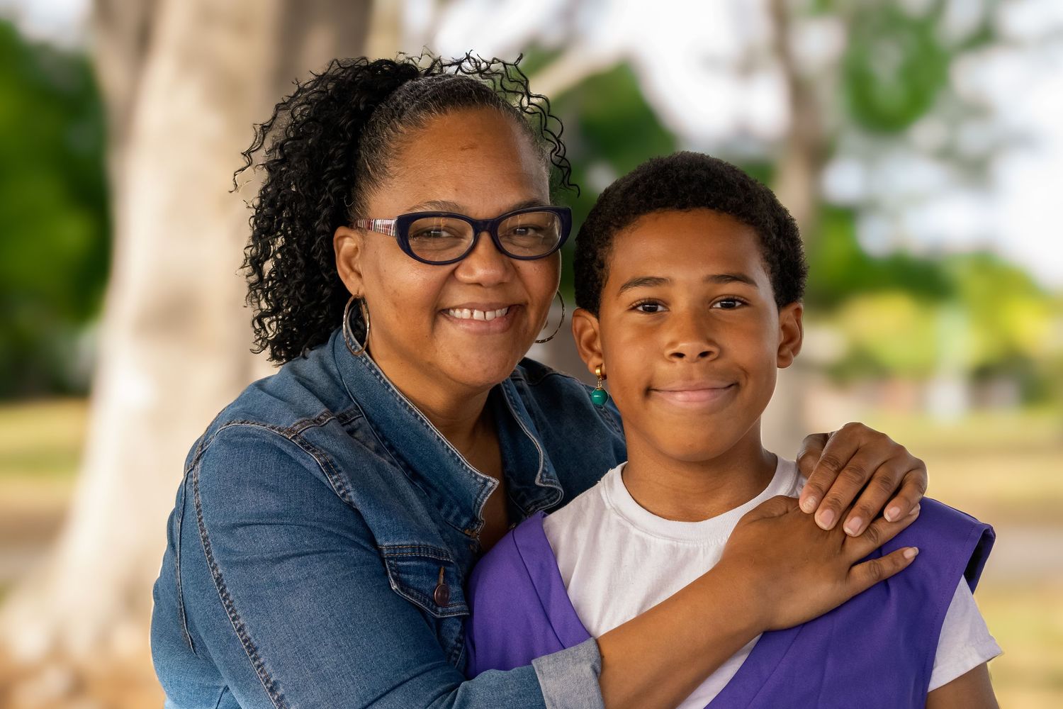 A heartwarming outdoor portrait showing affection between family members against a natural background.