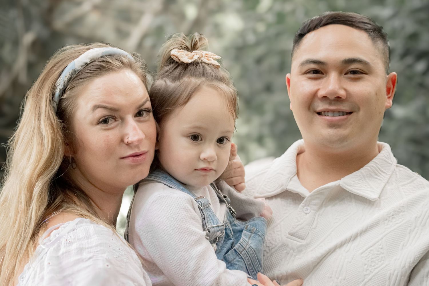 Family portrait session in white outfits against neutral background showing tender moments.