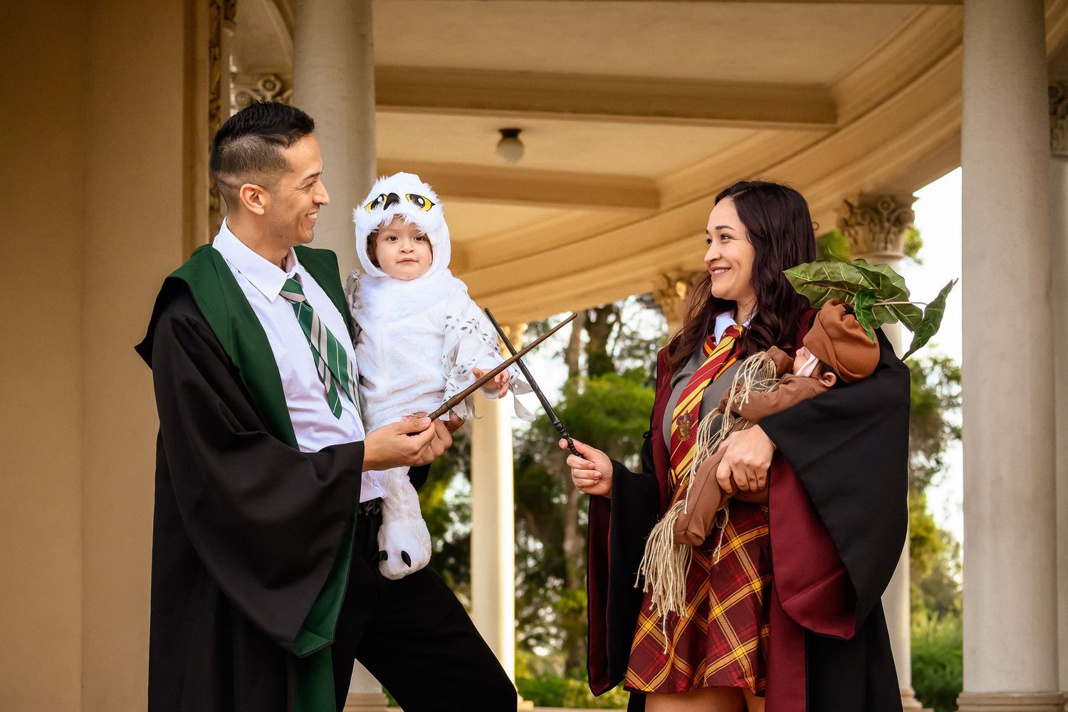 Family photo with parents in Hogwarts graduation robes posing with children in magical creature costumes.