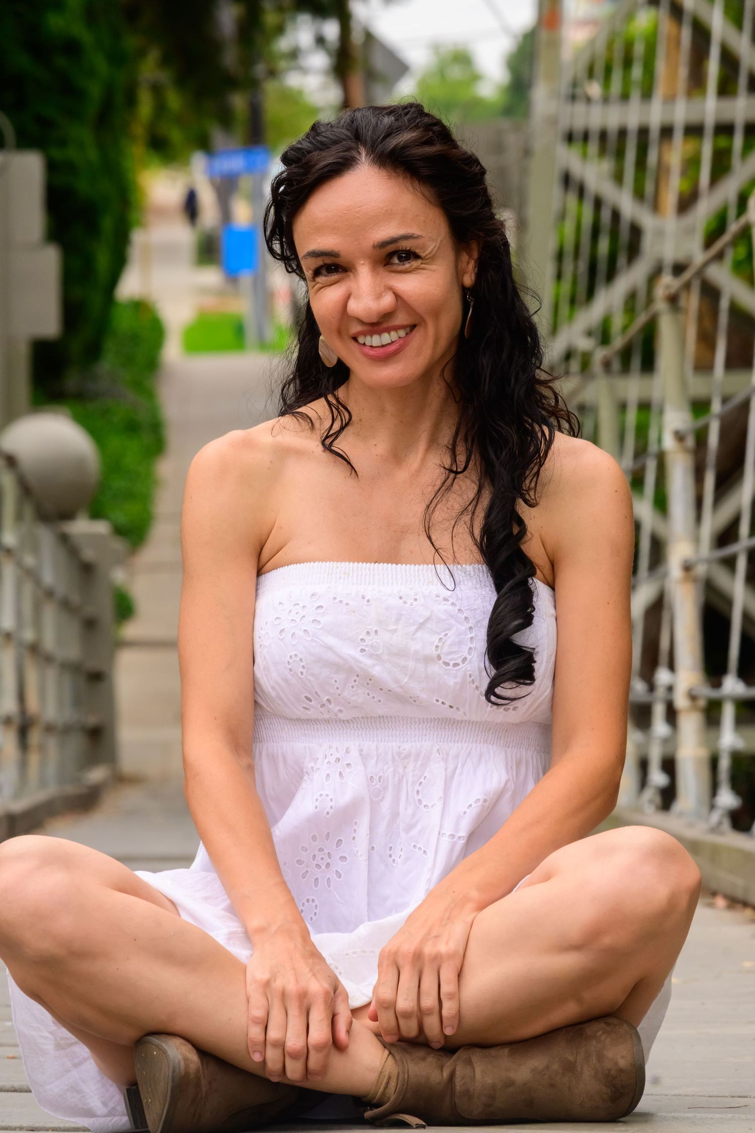 Person in white eyelet dress sitting casually on outdoor steps.