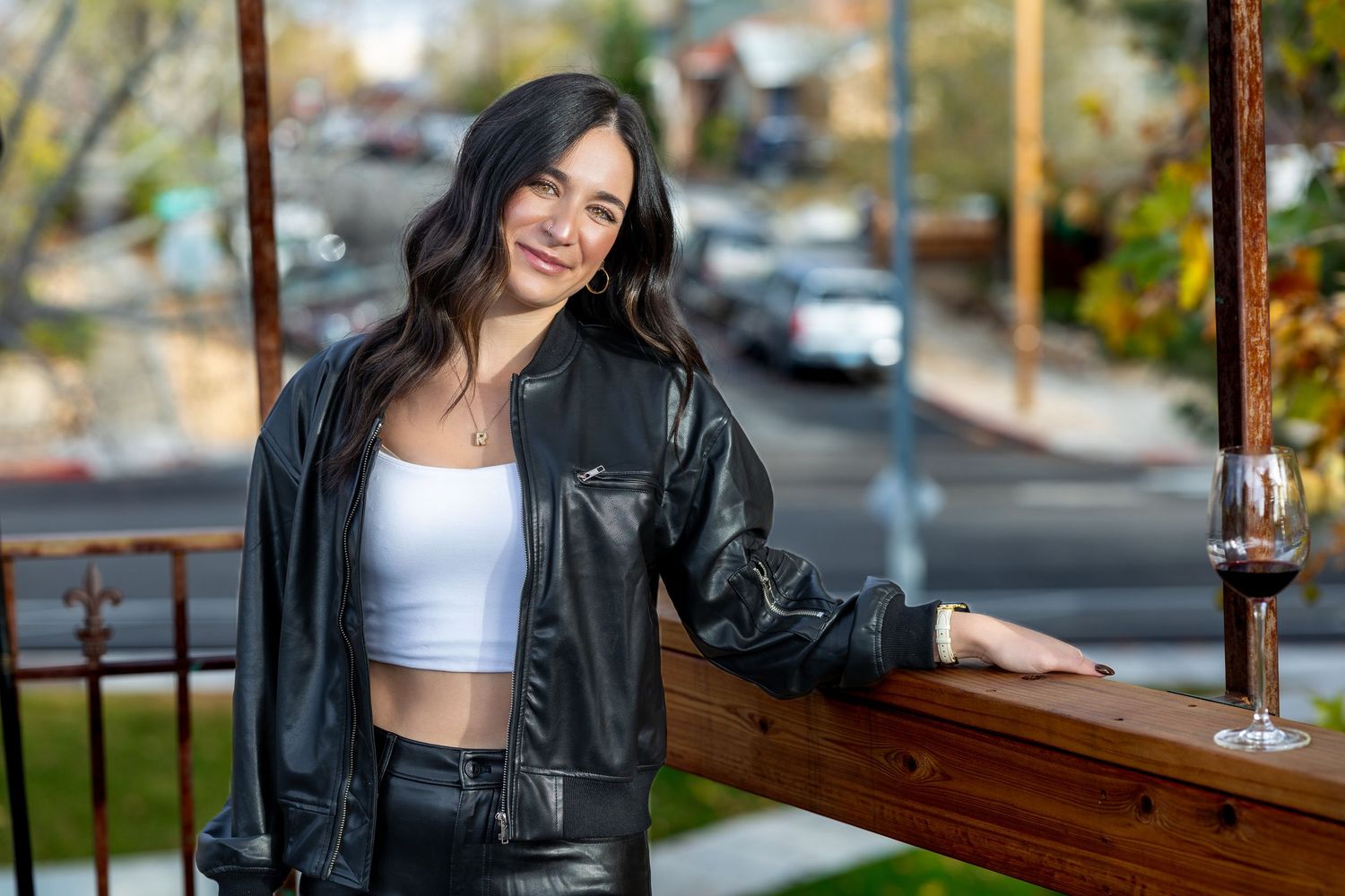 Athletic woman in black jacket and white sports bra poses confidently outdoors during fitness photoshoot.