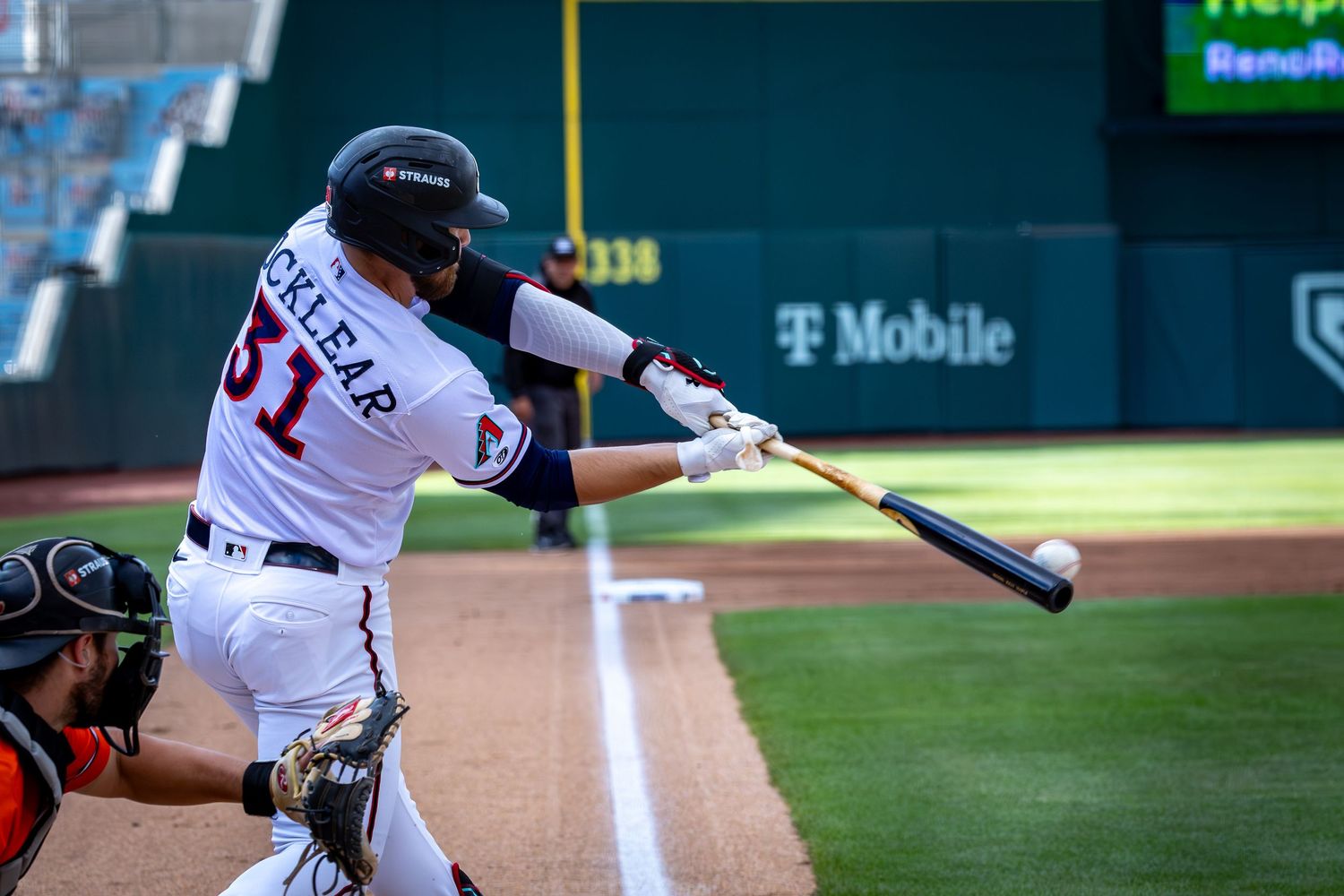 Baseball player #31 swings bat at pitch during night game at T-Mobile Park stadium.