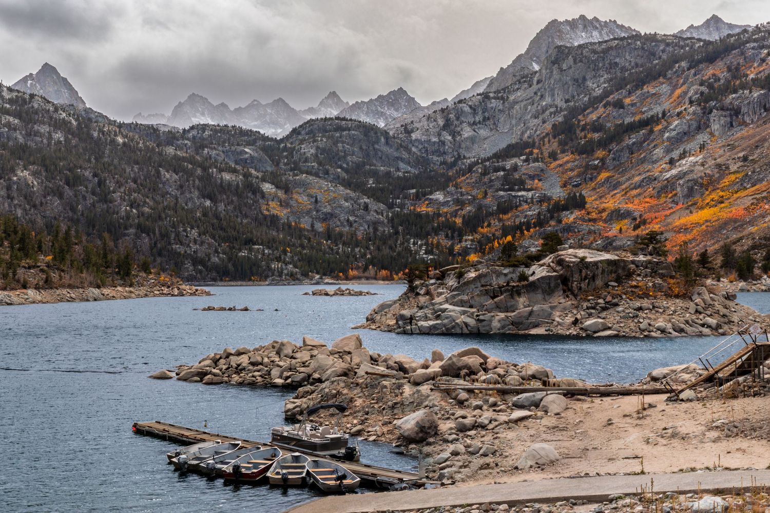 Dramatic mountain landscape with autumn colors surrounding Lake Sabrina in the Eastern Sierra Nevada Mountains during stormy weather.
