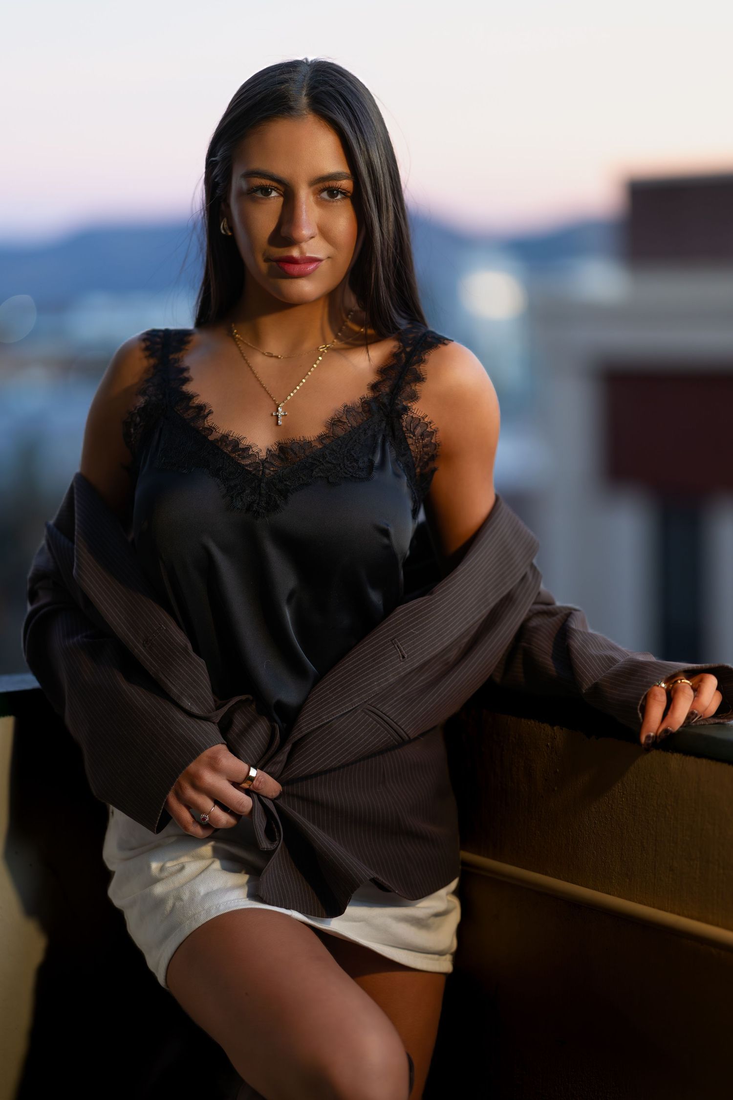 Elegant portrait session featuring a black dress against a blurred waterfront backdrop during golden hour.