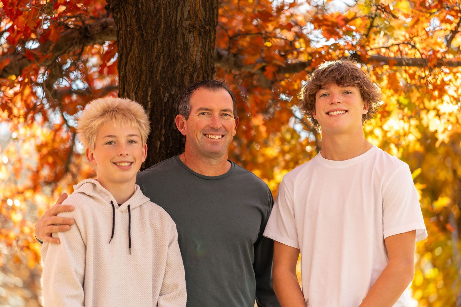 Group photo outdoors with vibrant orange autumn foliage and golden sunlight in the background.