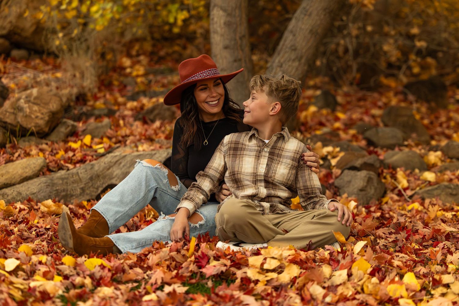 Couple relaxing together on colorful autumn leaves in park during fall season.
