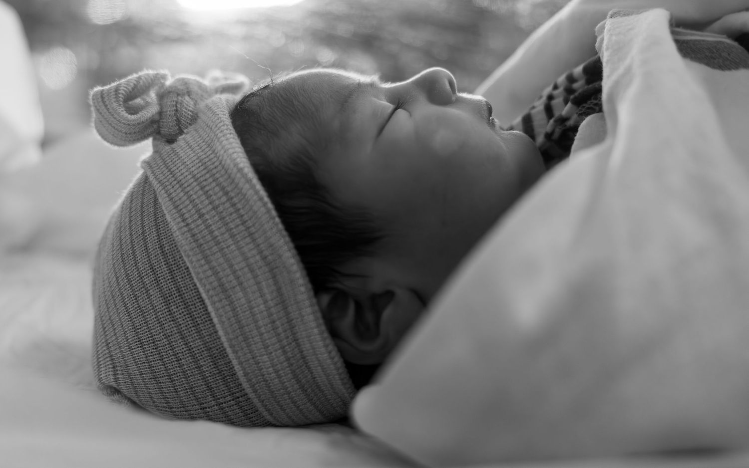 Black and white close-up of someone resting peacefully in a knit hat.