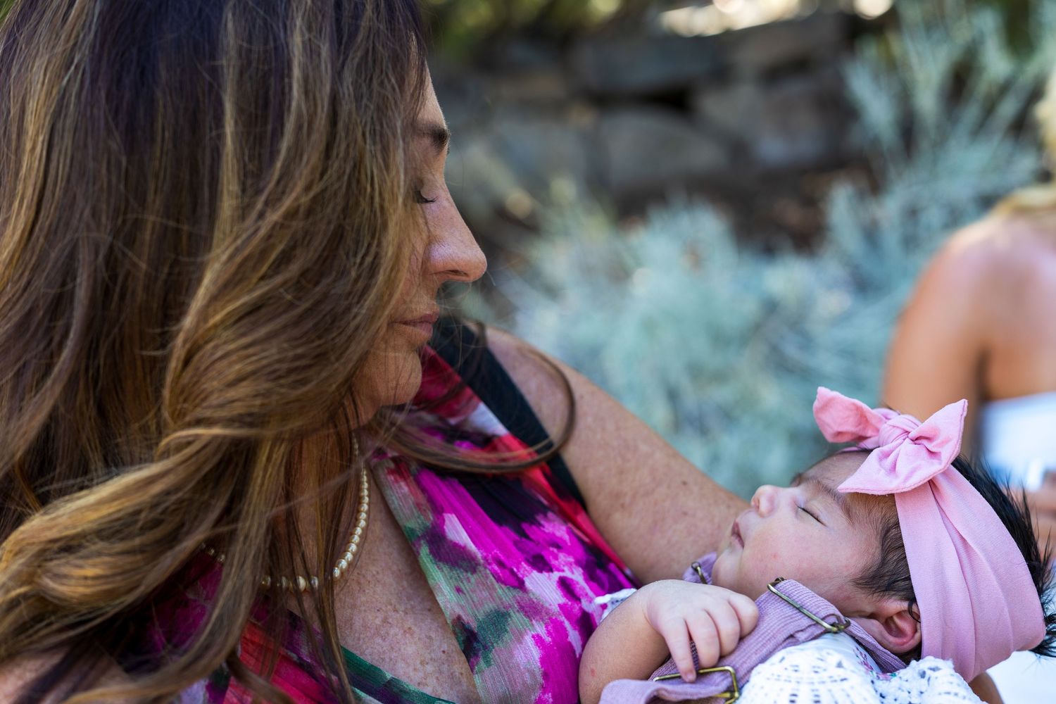 Tender moment between parent and baby outdoors among desert plants.