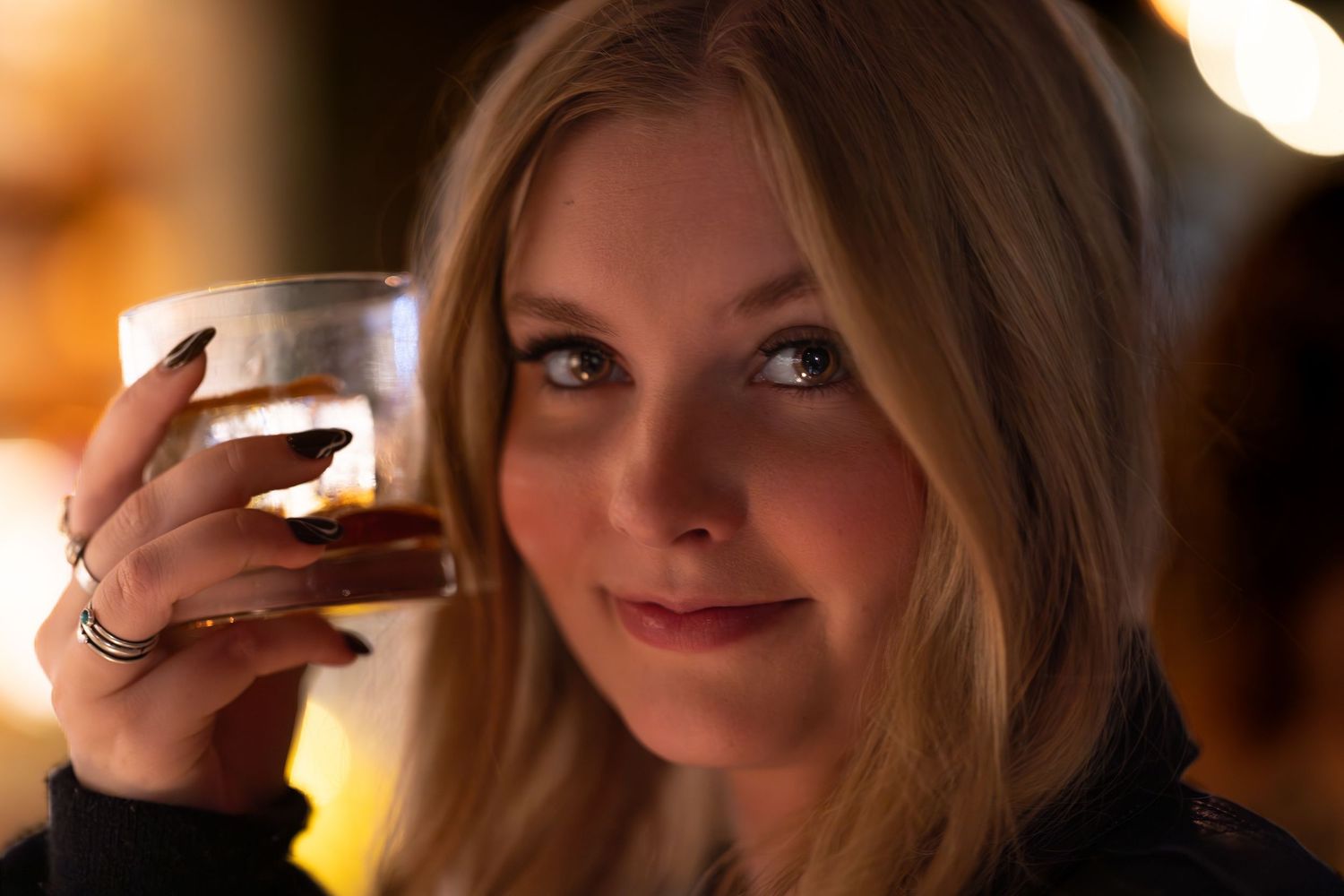 A series of people toasting with shot glasses at a dimly lit bar or party setting.