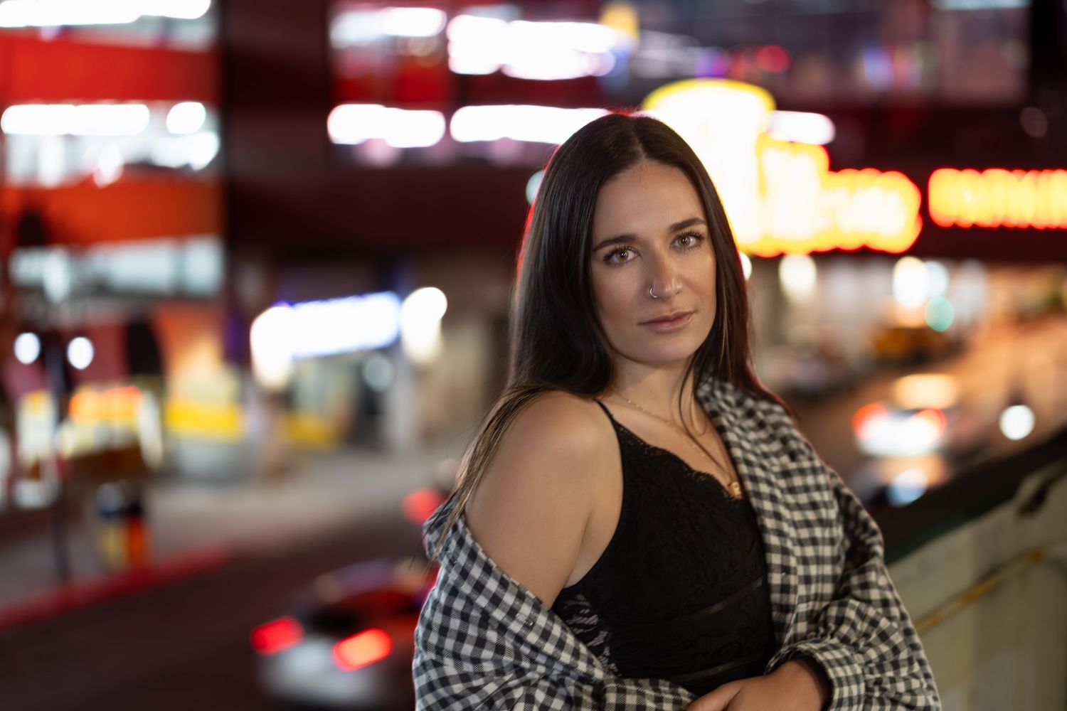 A person in a black and white houndstooth top poses in various positions against an urban nighttime backdrop.