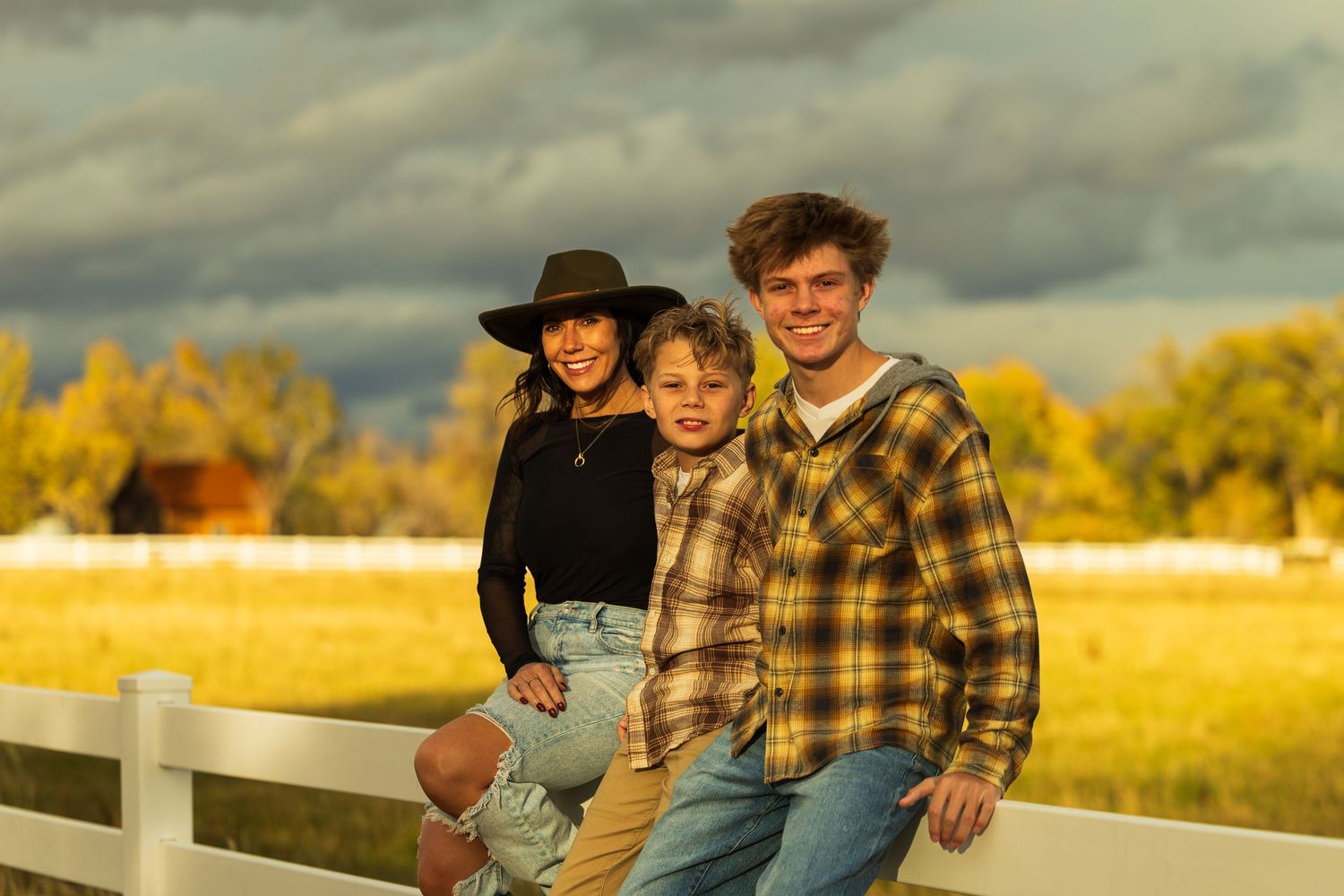 People enjoying a sunset in a golden field with dramatic clouds overhead during autumn.