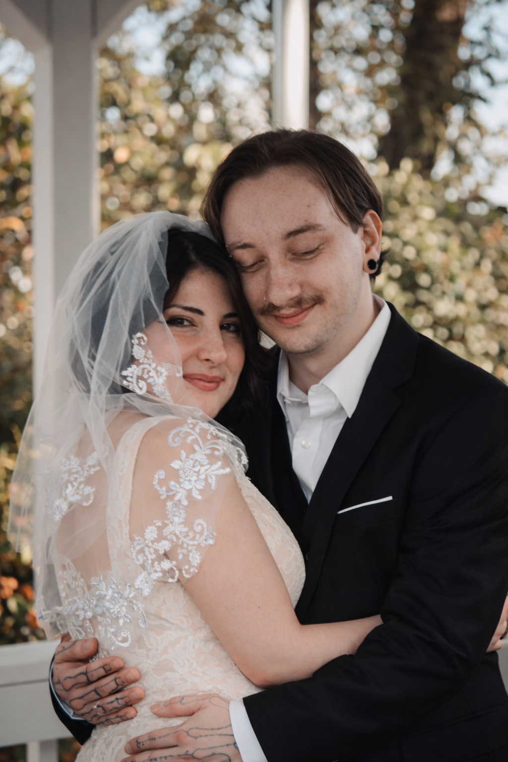 A couple shares intimate moments during their wedding photoshoot on a sunlit porch.