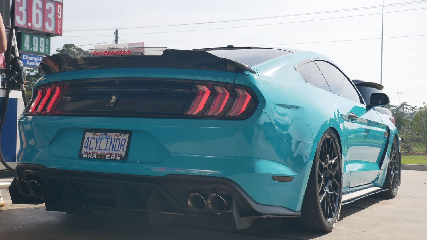 Rear view of a turquoise Ford Mustang Shelby GT500 showcasing distinctive taillights and quad exhaust.