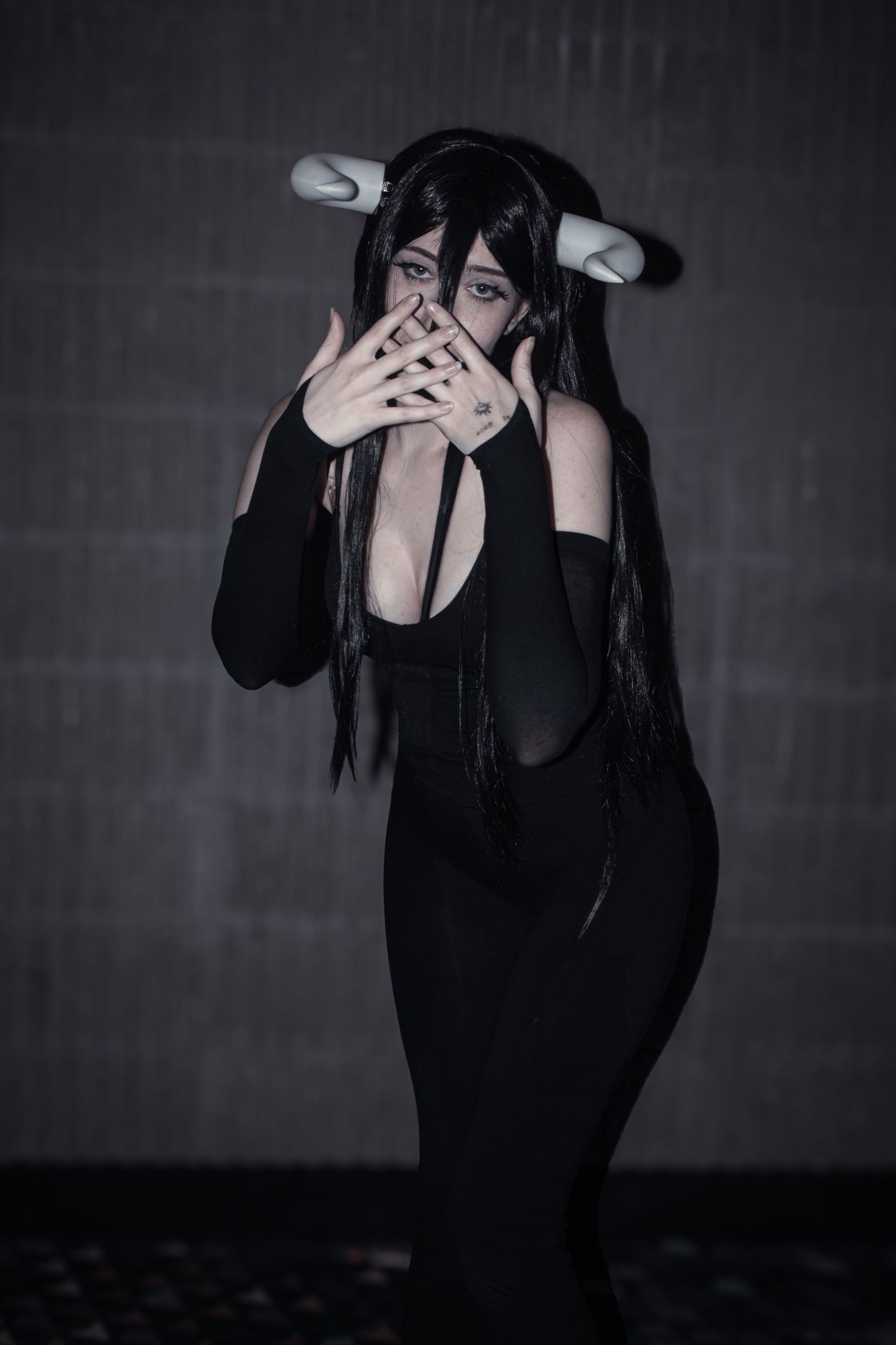 Dark anime-inspired cosplay featuring black bodysuit and white horned headpiece.
