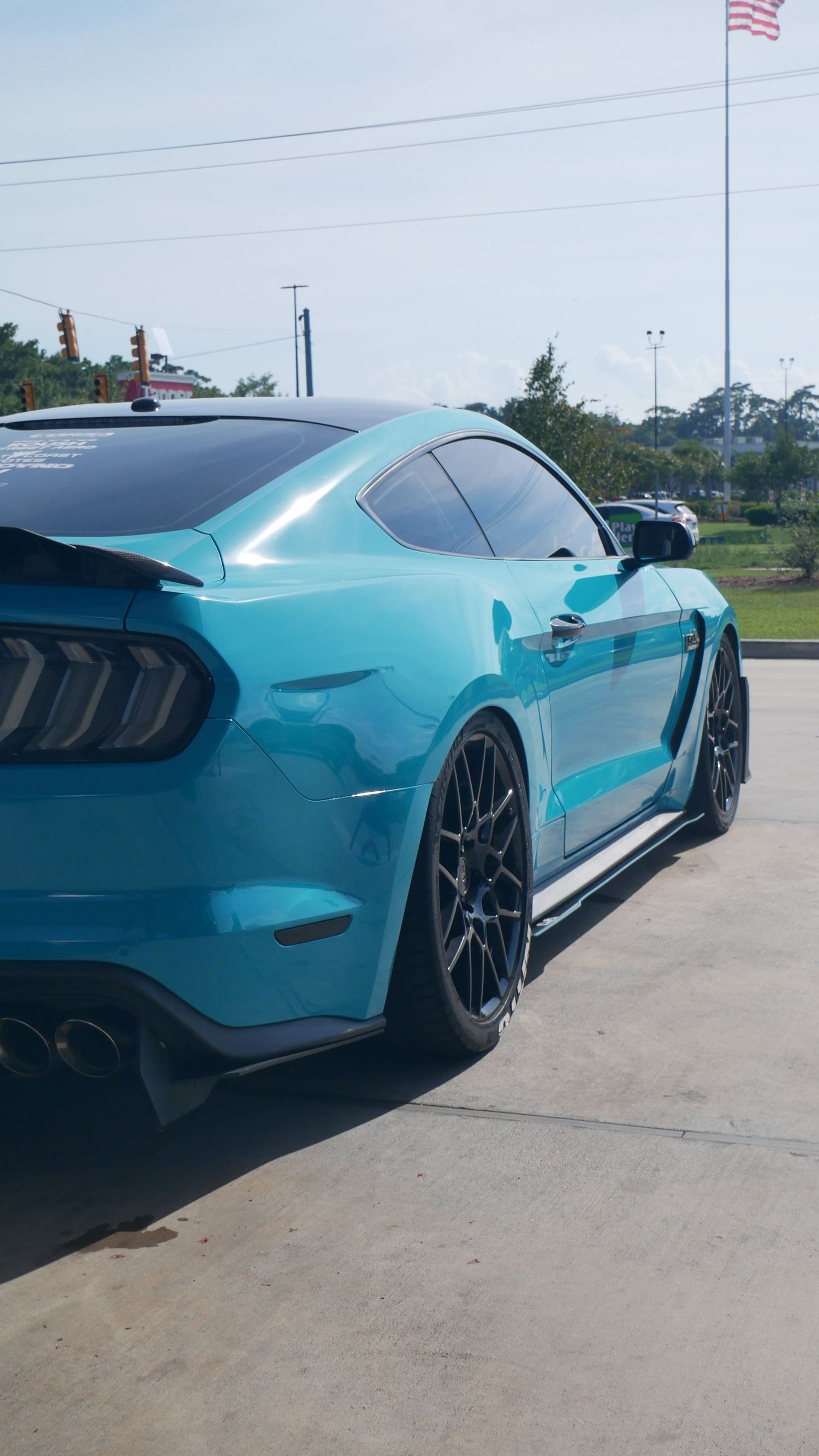 Rear quarter view of a turquoise Mustang GT showing custom wheels and body modifications.