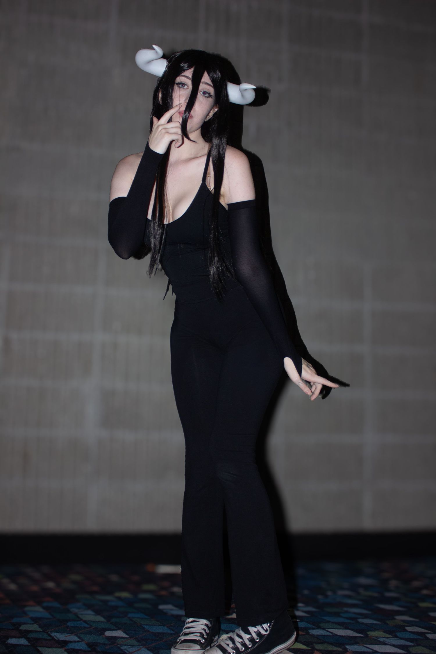 A person wearing all black strikes moody poses in a dark studio setting.