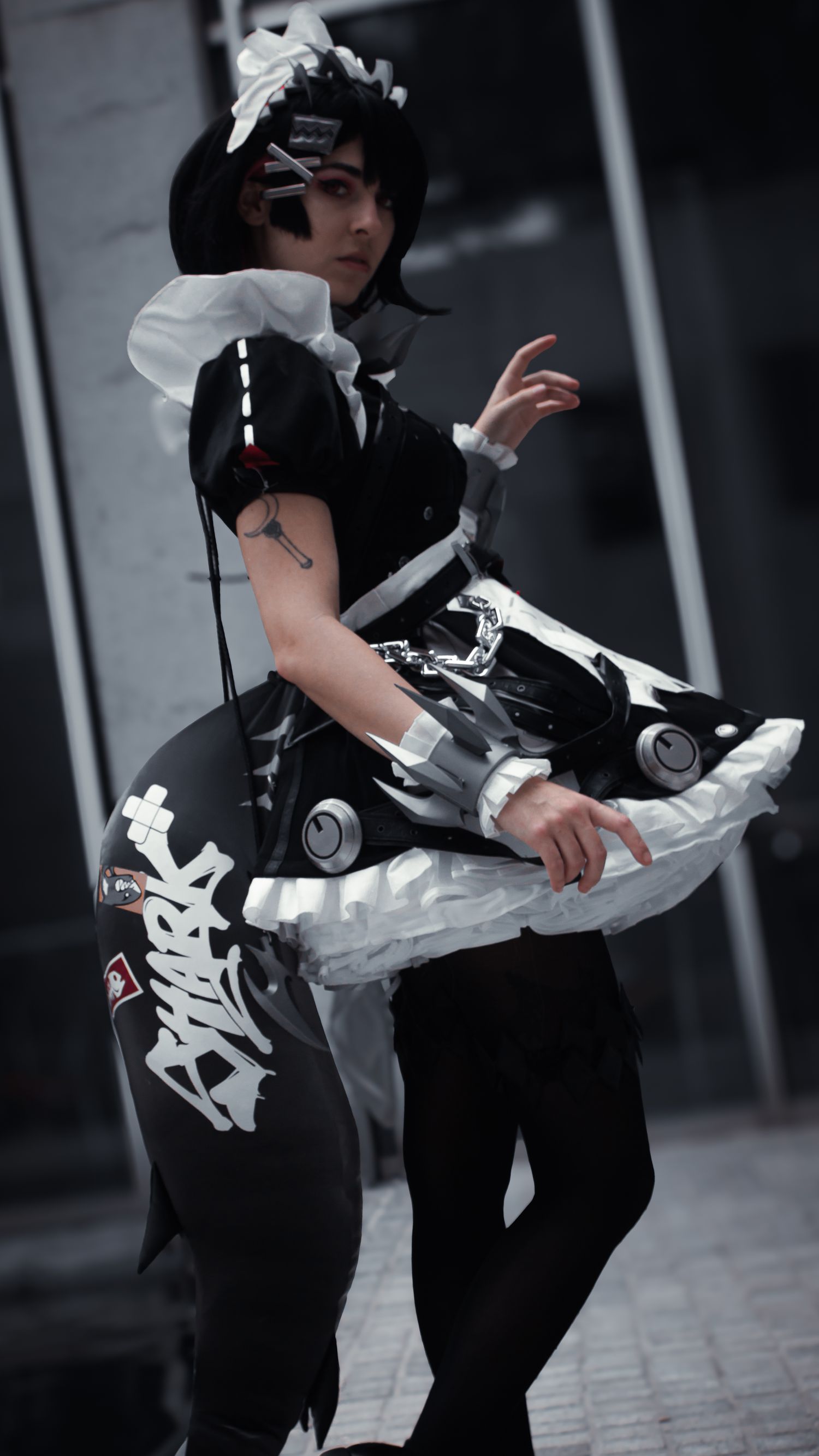 Cosplayer in black and white maid outfit striking dynamic pose.