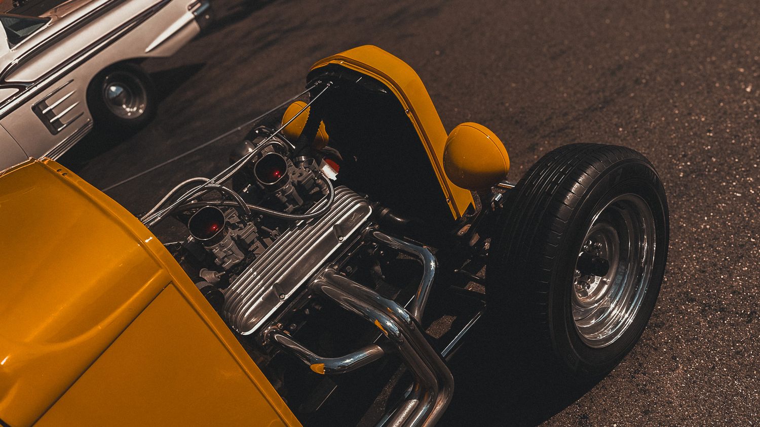 Modified yellow sports car with exposed engine and custom wheels on display.