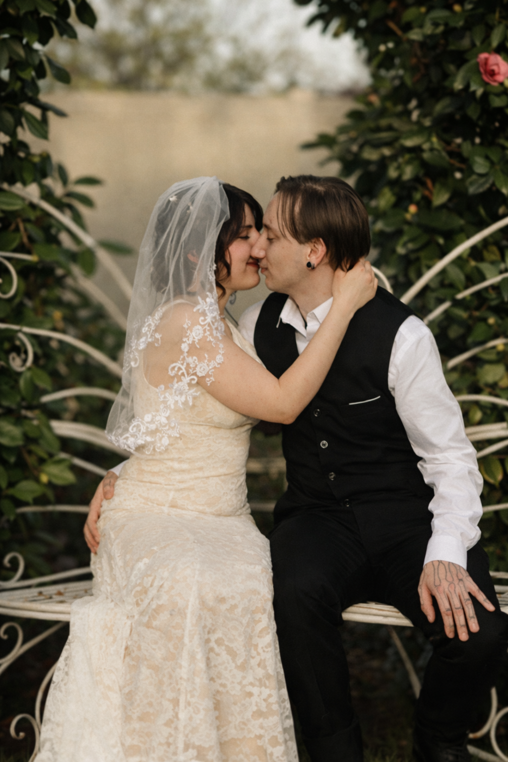 A romantic wedding couple shares intimate moments in a garden setting with lush greenery in the background.