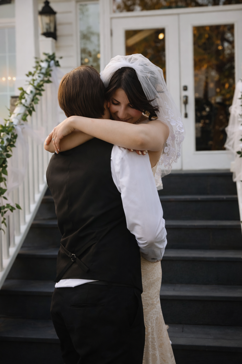 Two figures embrace in an intimate moment on a porch with white columns and dark steps.
