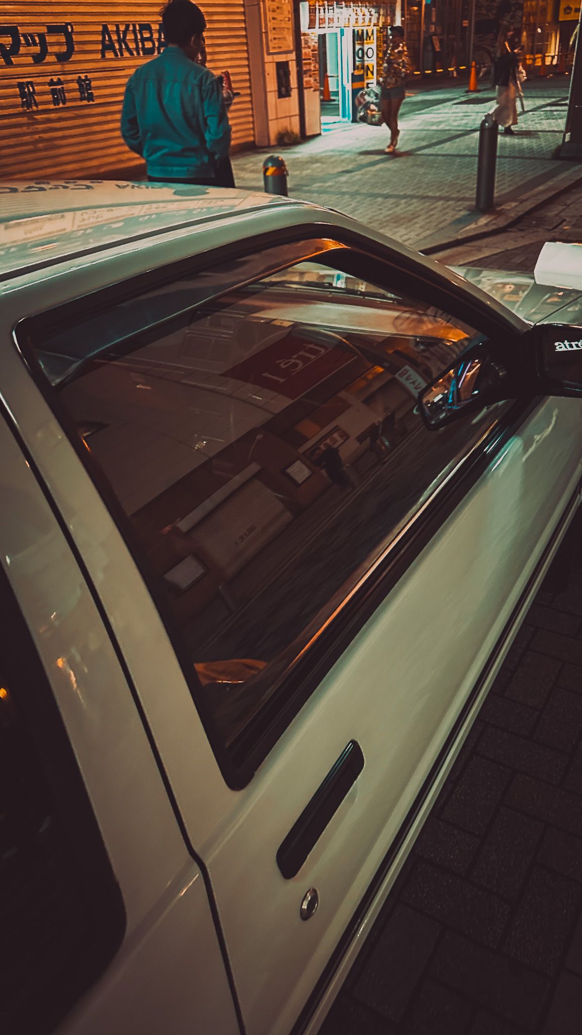 High angle view of white car roof and windshield reflecting city lights at night.