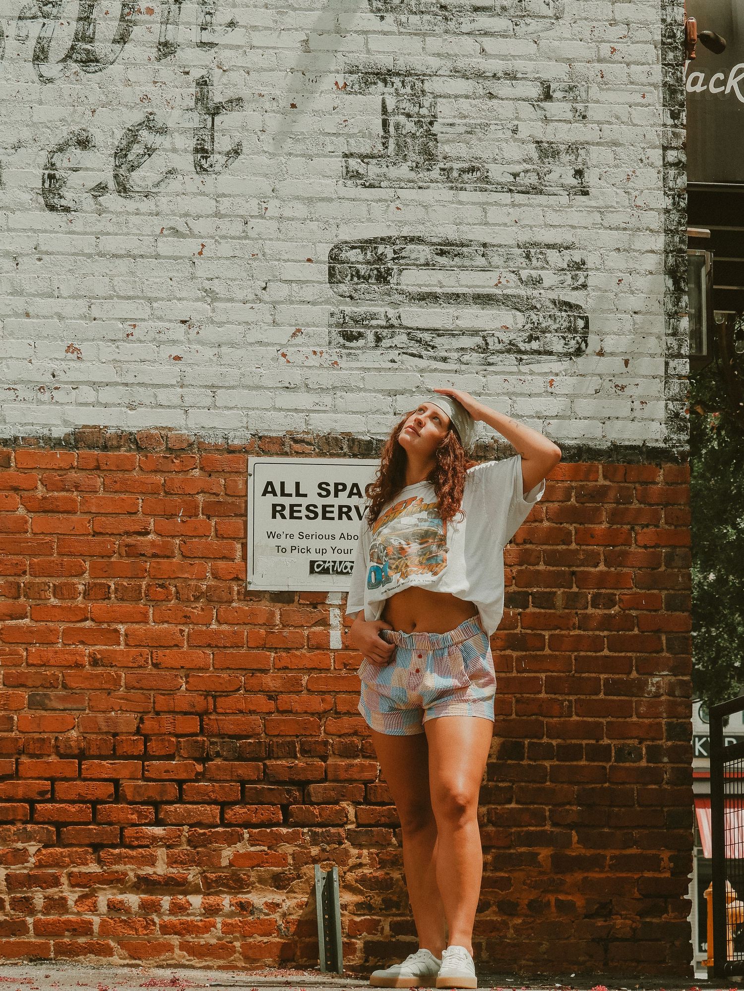 Person in denim shorts poses against exposed brick wall in sequence of four artistic film photos.