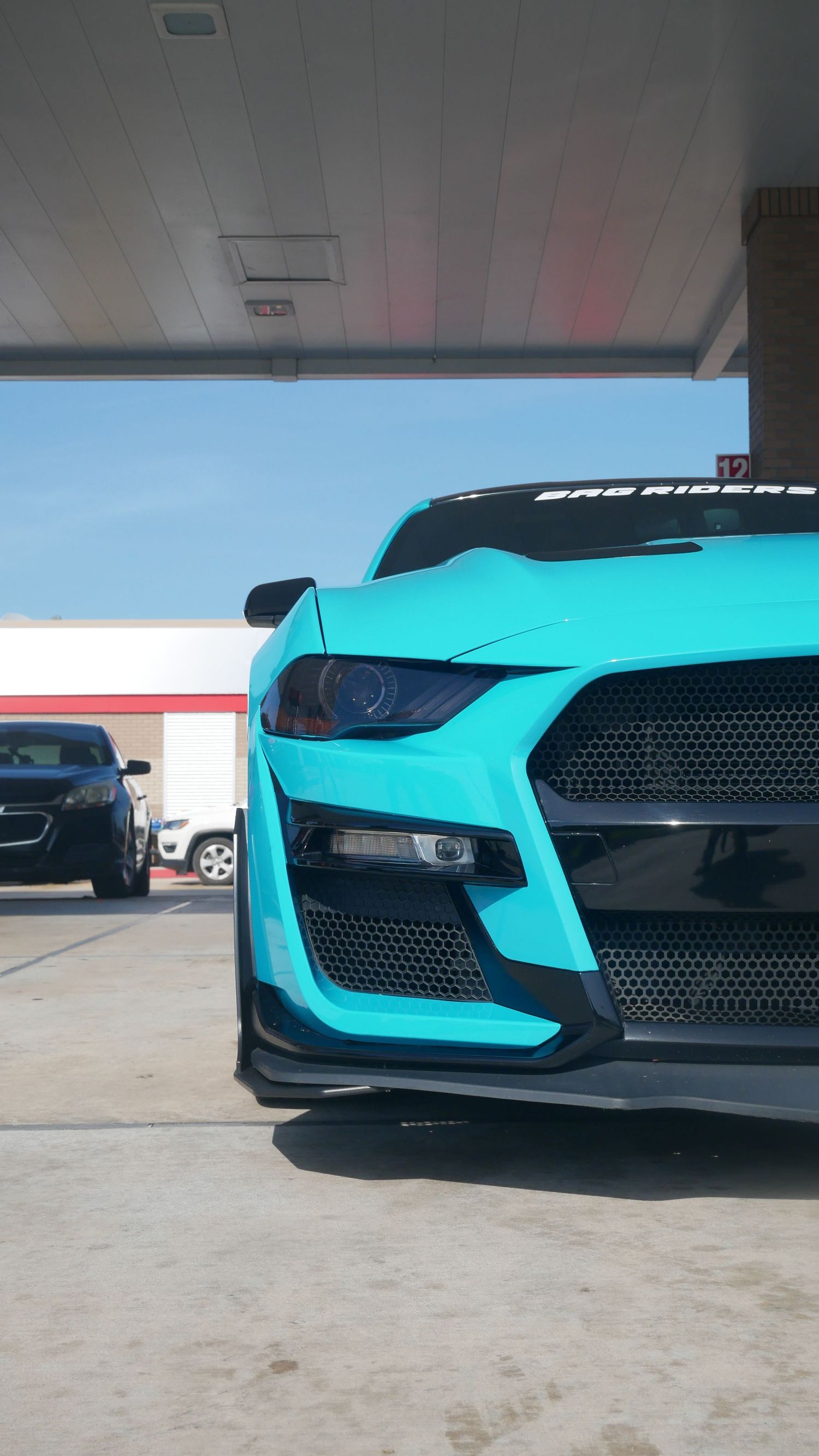 Close-up view of a turquoise Mustang GT500's front end showing aggressive grille design and hood details.