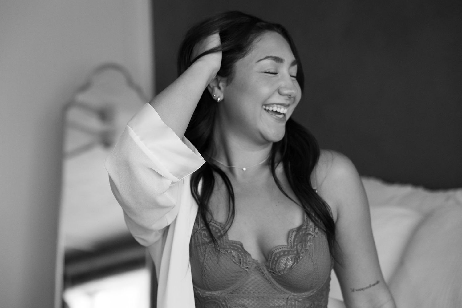 Black and white portrait of a woman in lingerie laughing joyfully while wearing a white shirt.