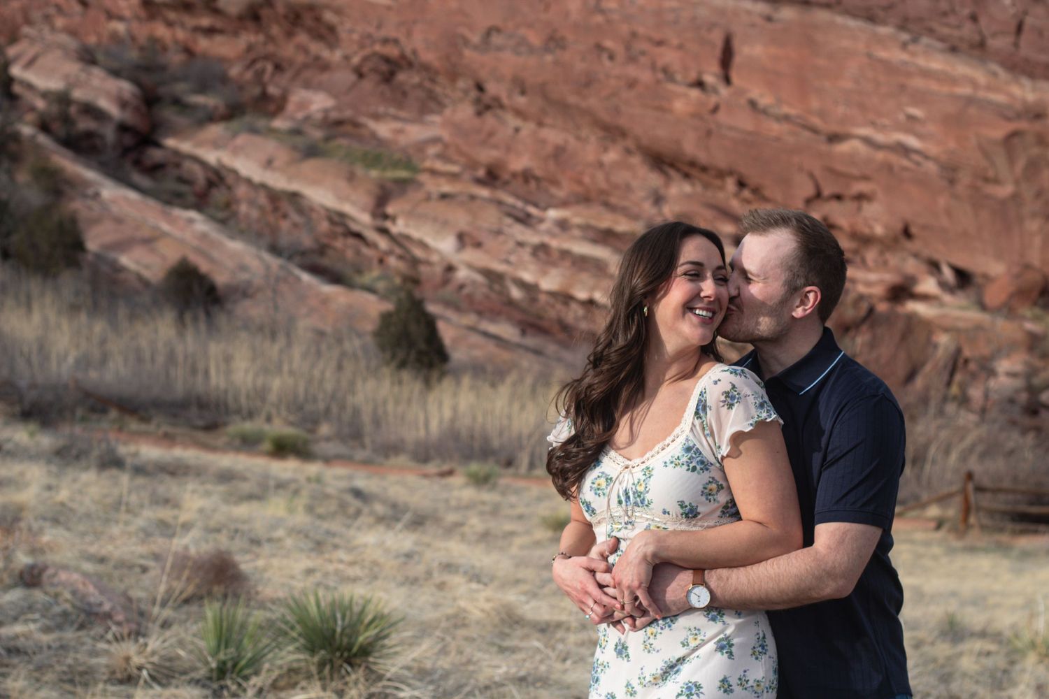Newly engaged couple embraces during their engagement shoot at Red Rocks in Morrison, Colorado