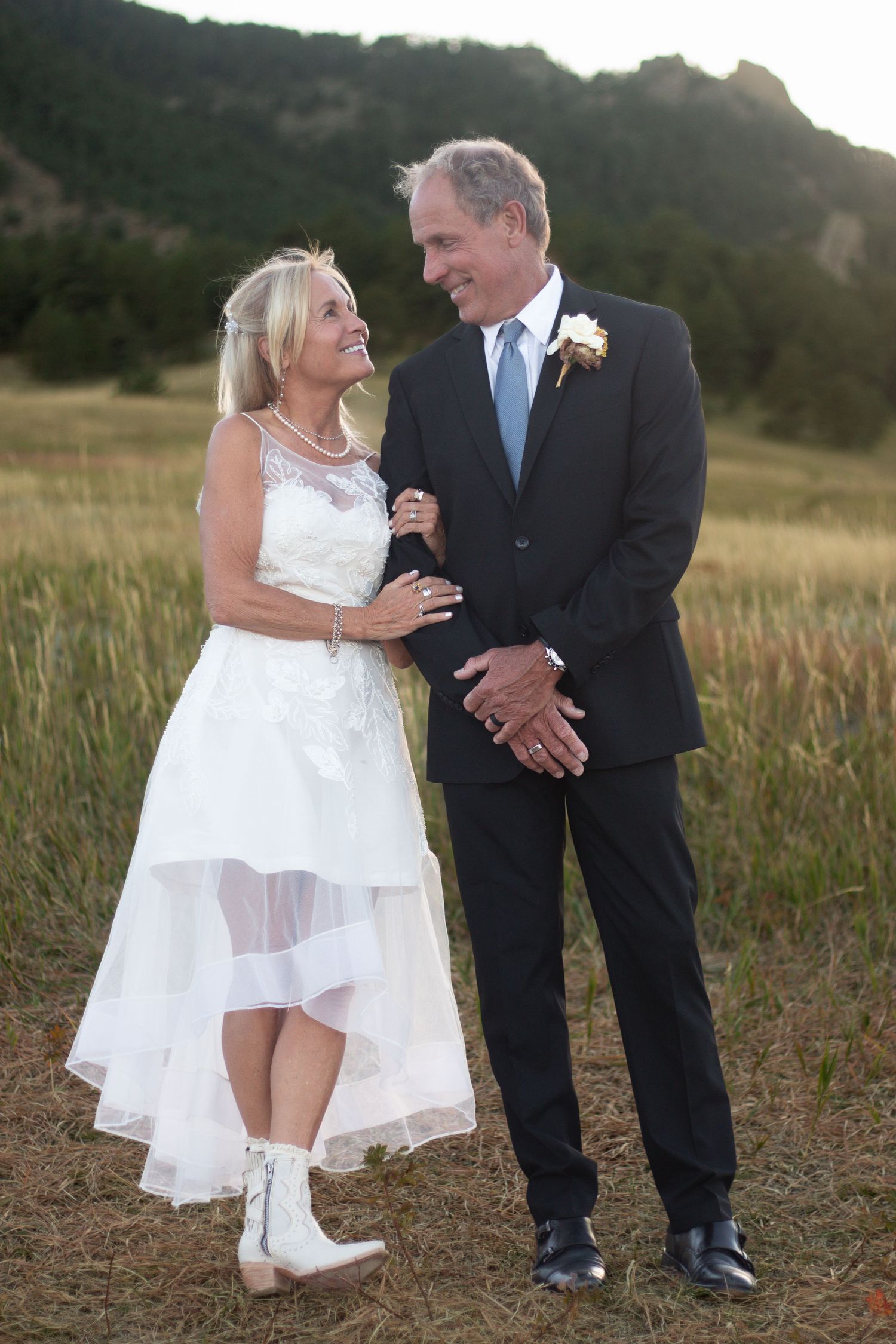 Wedding couple shares playful moment together in a rustic field at sunset.