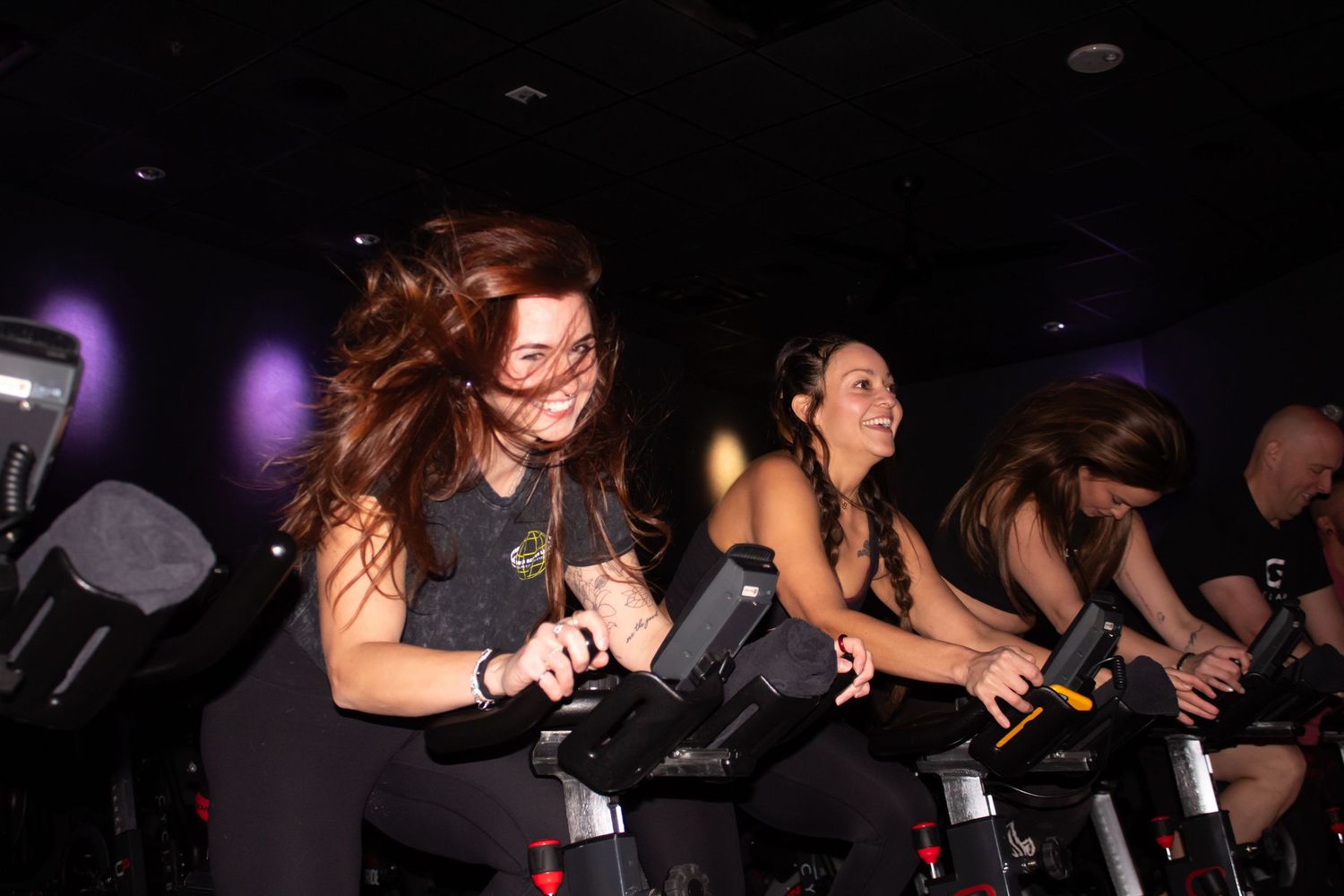 Several enthusiastic participants riding stationary bikes at Cyclebar during a high-energy indoor cycling class.