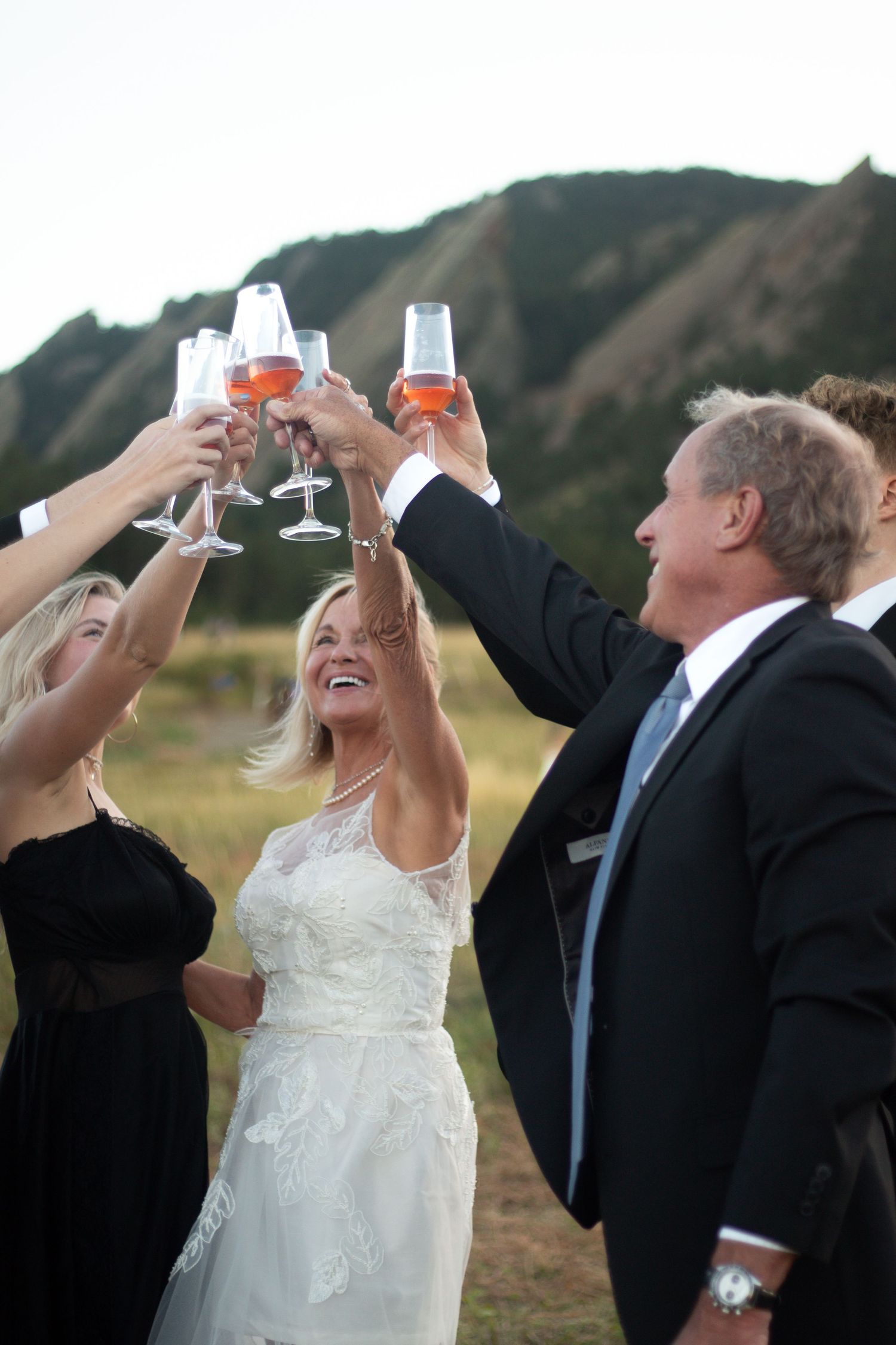 A bride and groom share a toast with raised glasses against a mountain backdrop in a progressive photo sequence.
