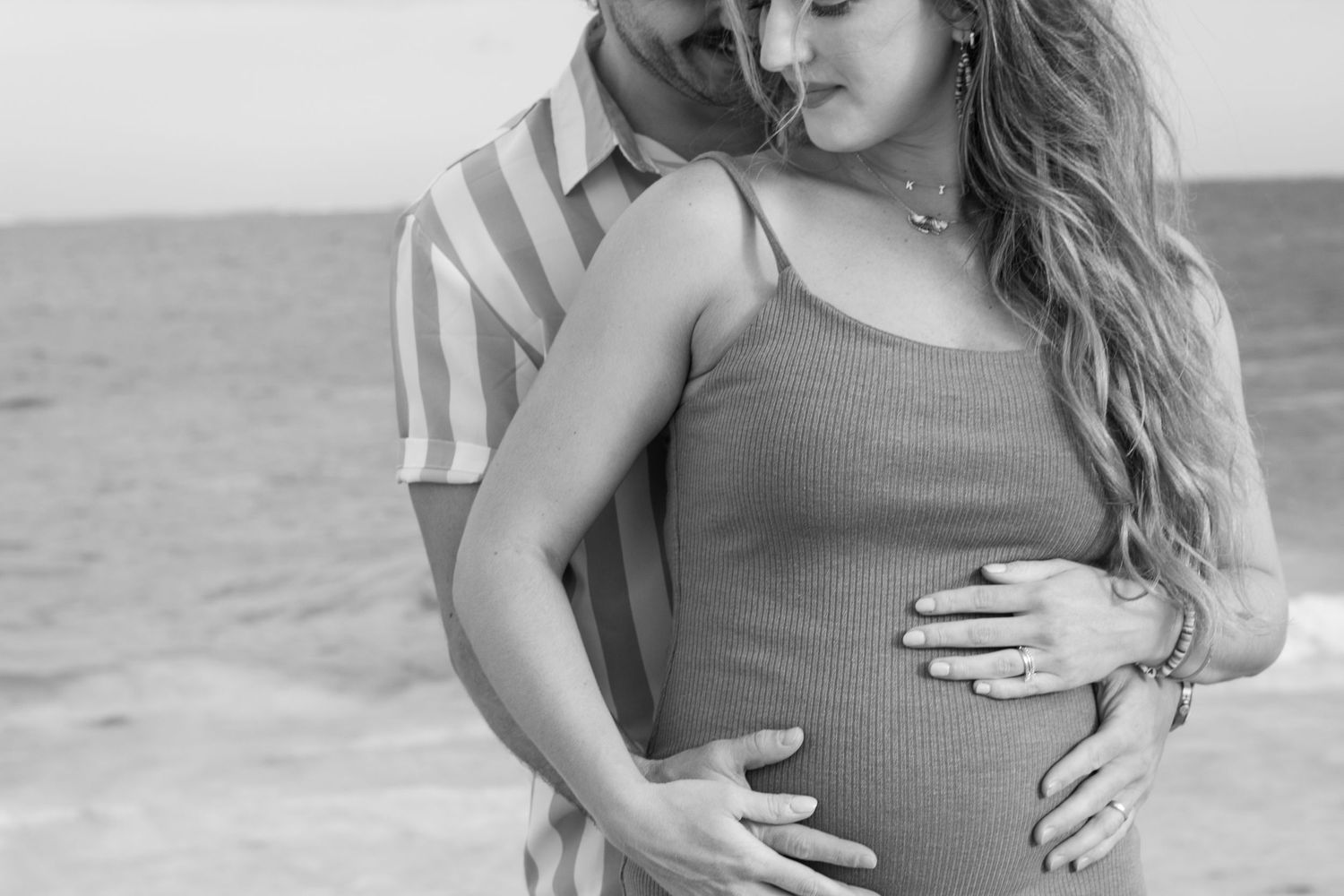 A progression of maternity photos showing a woman in a gray dress on a beach as her pregnancy advances.