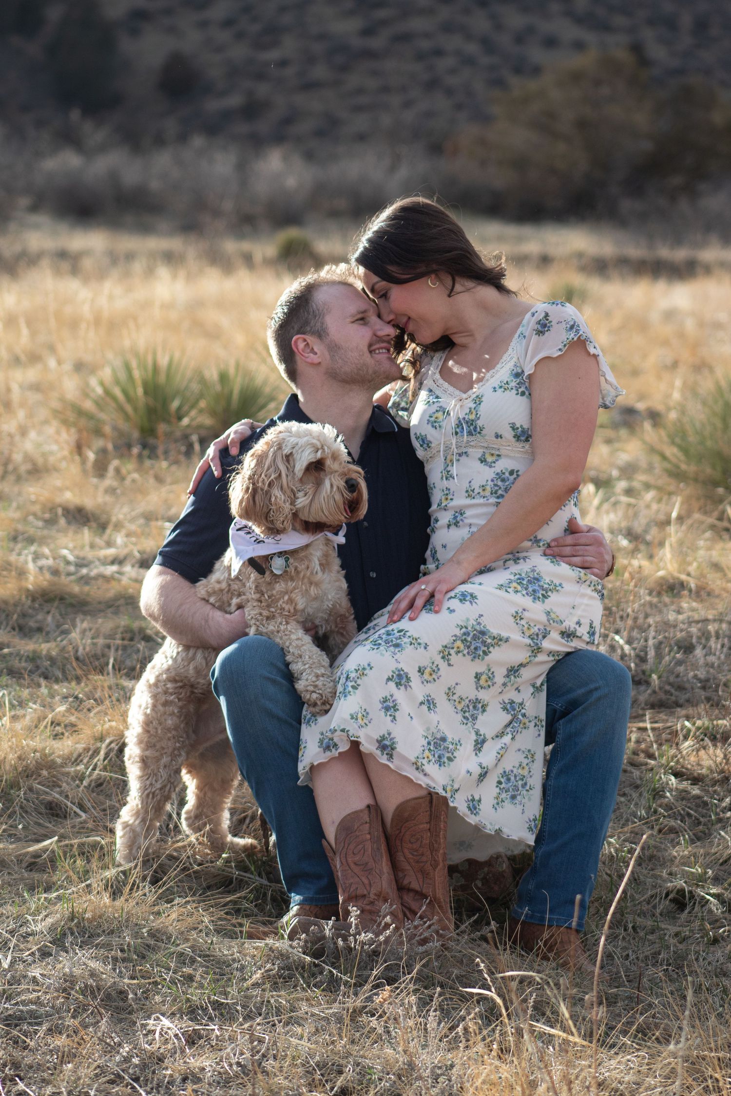 A couple shares a romantic moment outdoors with their fluffy goldendoodle dog during a Red Rocks photoshoot.