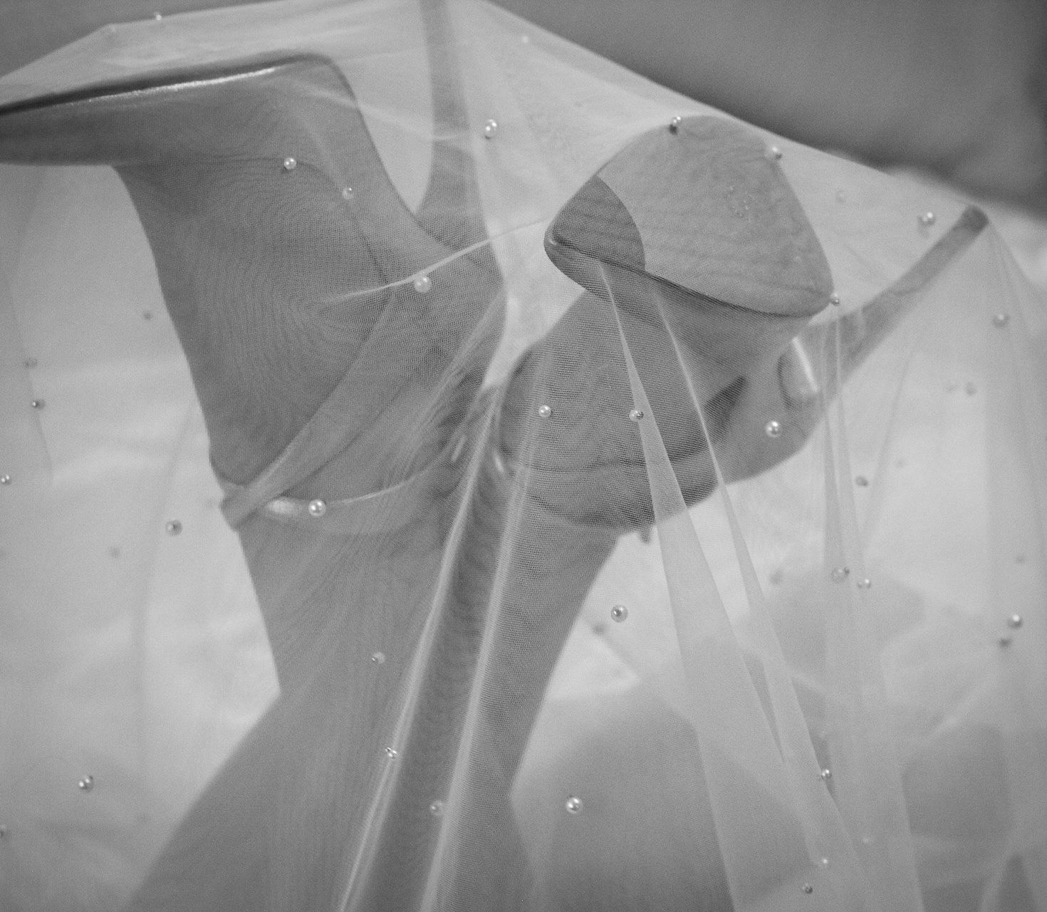 Black and white image shows woman's feet in high heels, draped with a veil