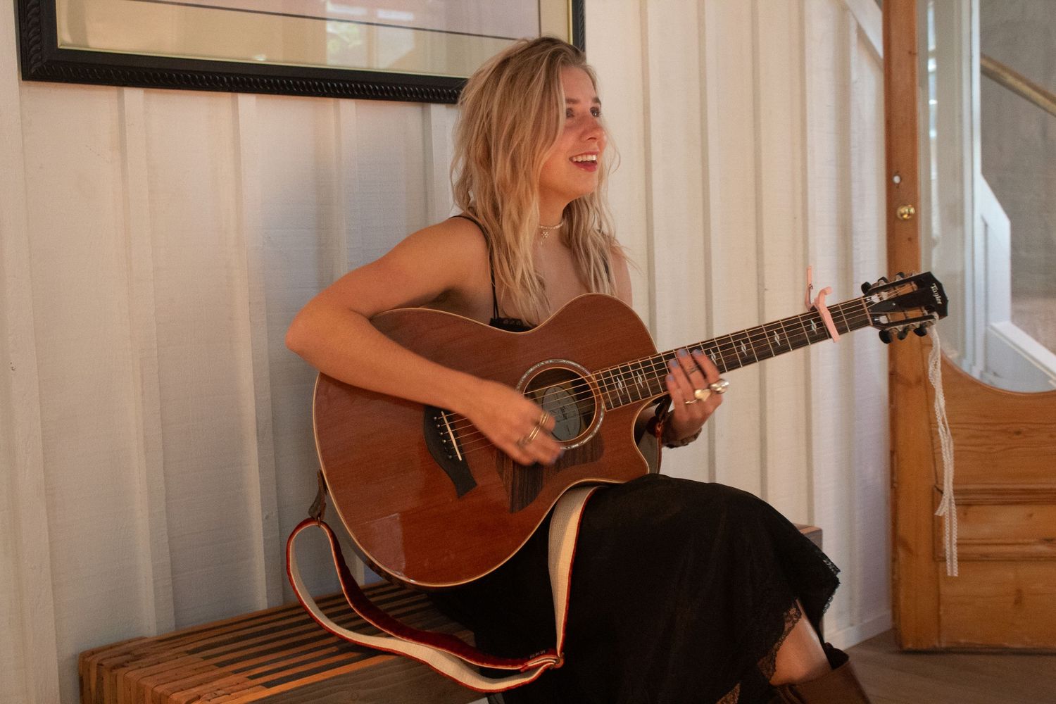 Journey Tupper plays acoustic guitar sitting near window in four similar poses showing progression of movement.