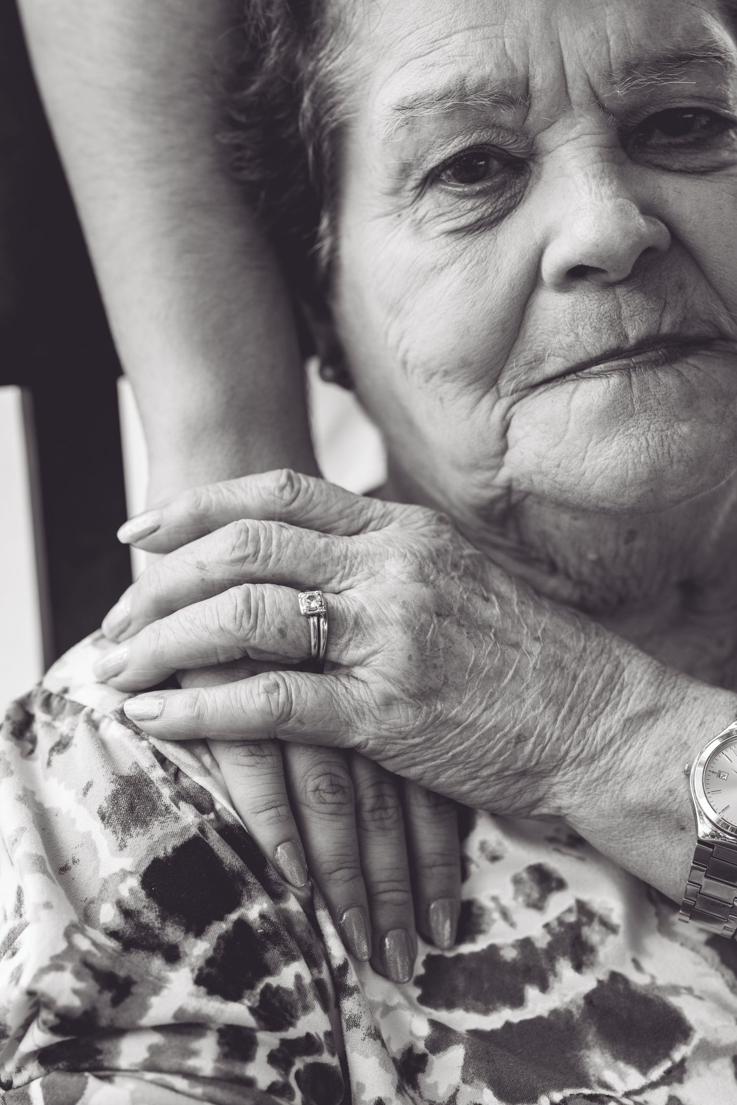 Black and white close-up of an older woman's hands gently holding a teen's hand during a multigenerational family session