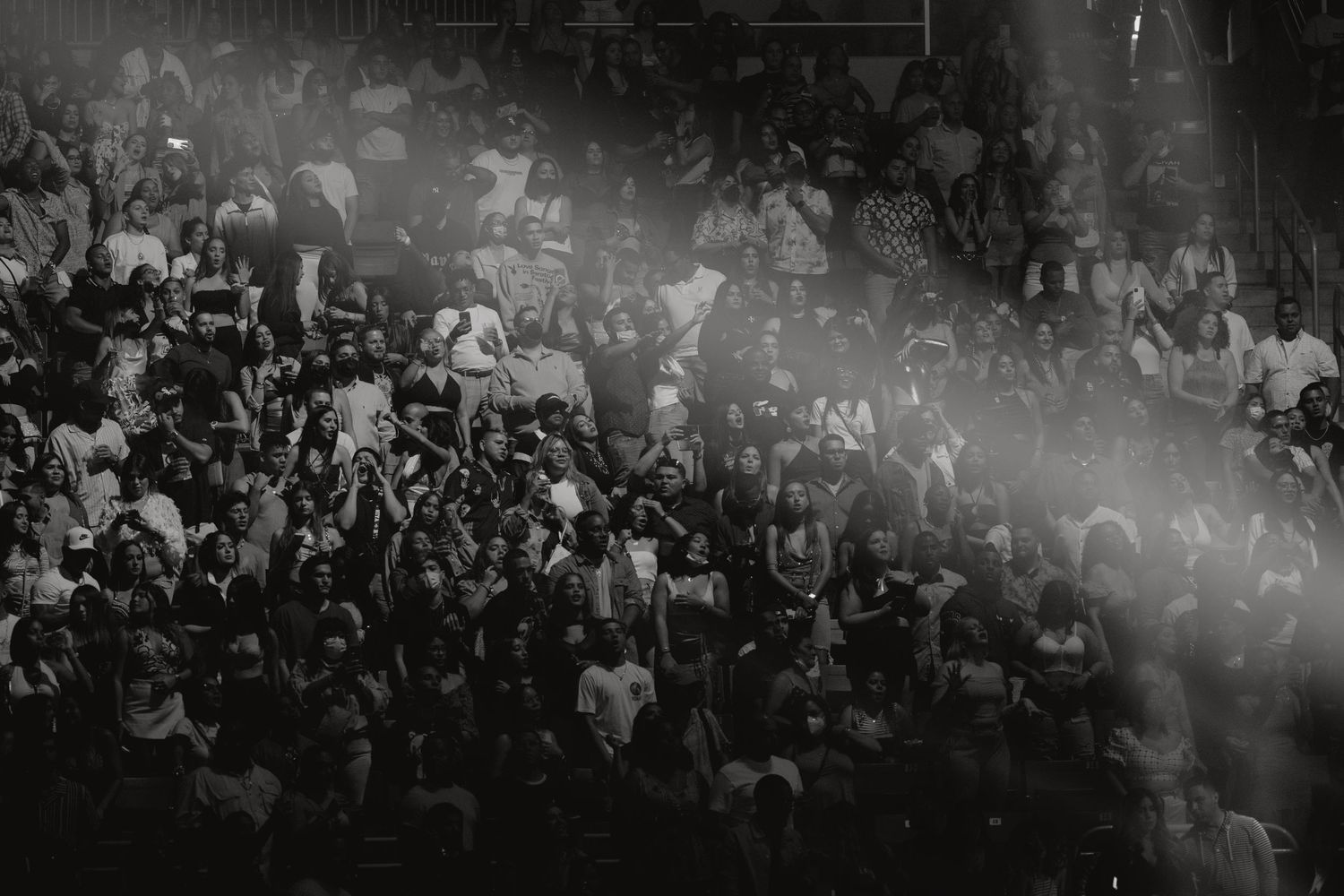 Black and white photo of a large crowd at a live concert event with dramatic stage lighting.