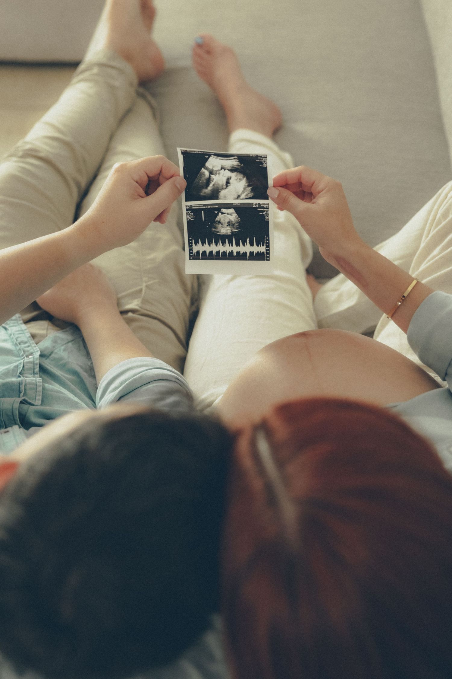 Expecting couple holding ultrasound photos together during an intimate at-home maternity session