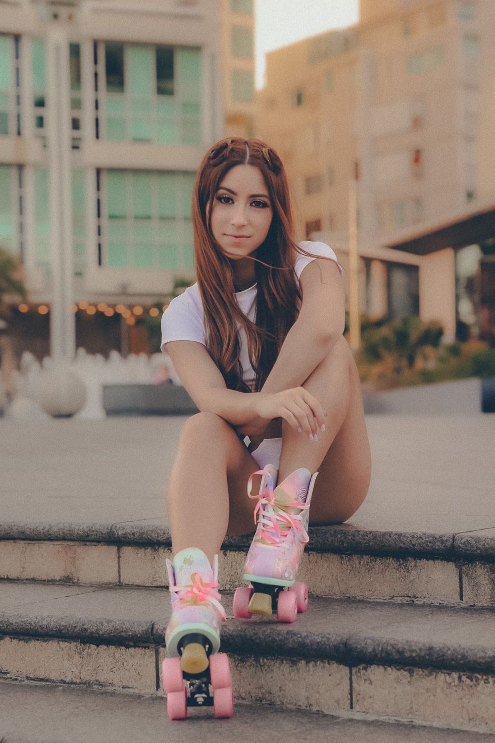 Lifestyle portrait of red-haired model wearing colorful roller skates in an urban setting