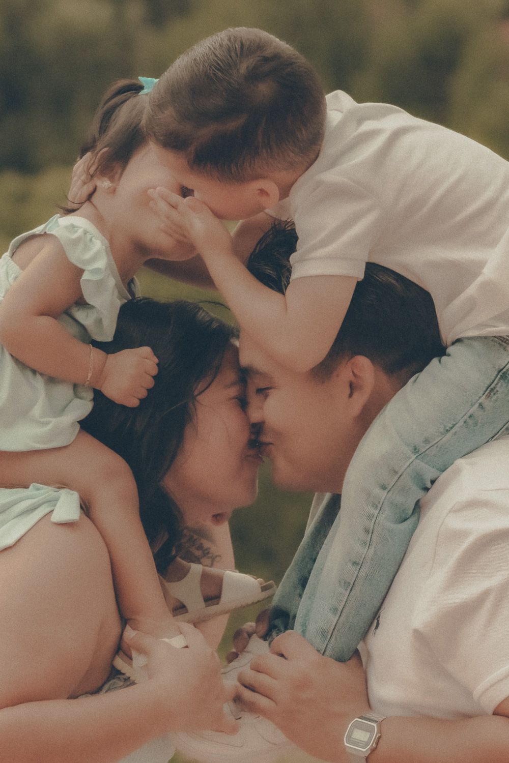 Intimate family portrait of parents touching foreheads while their children cuddle around them