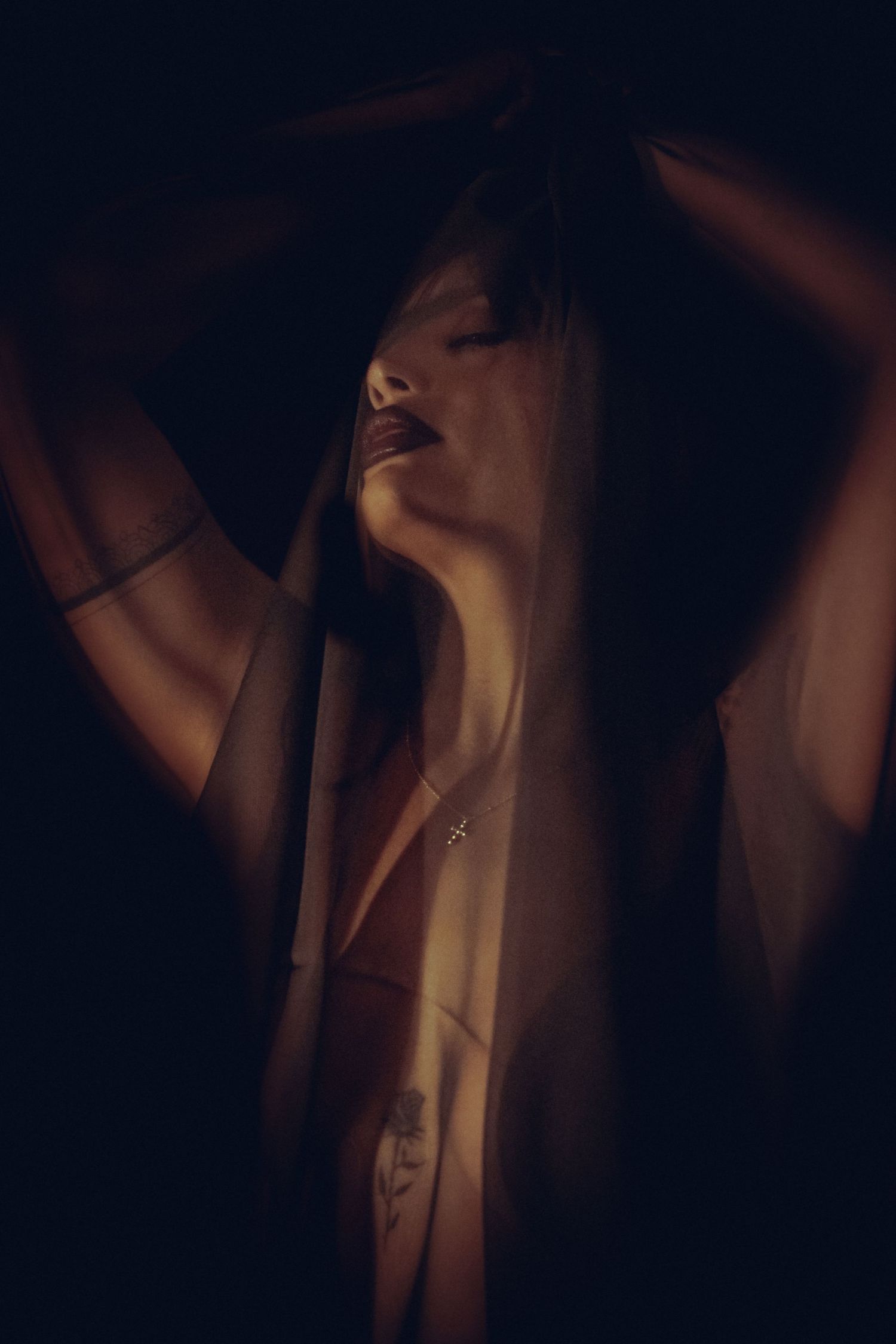 Moody cinematic portrait of female model photographed through sheer black fabric