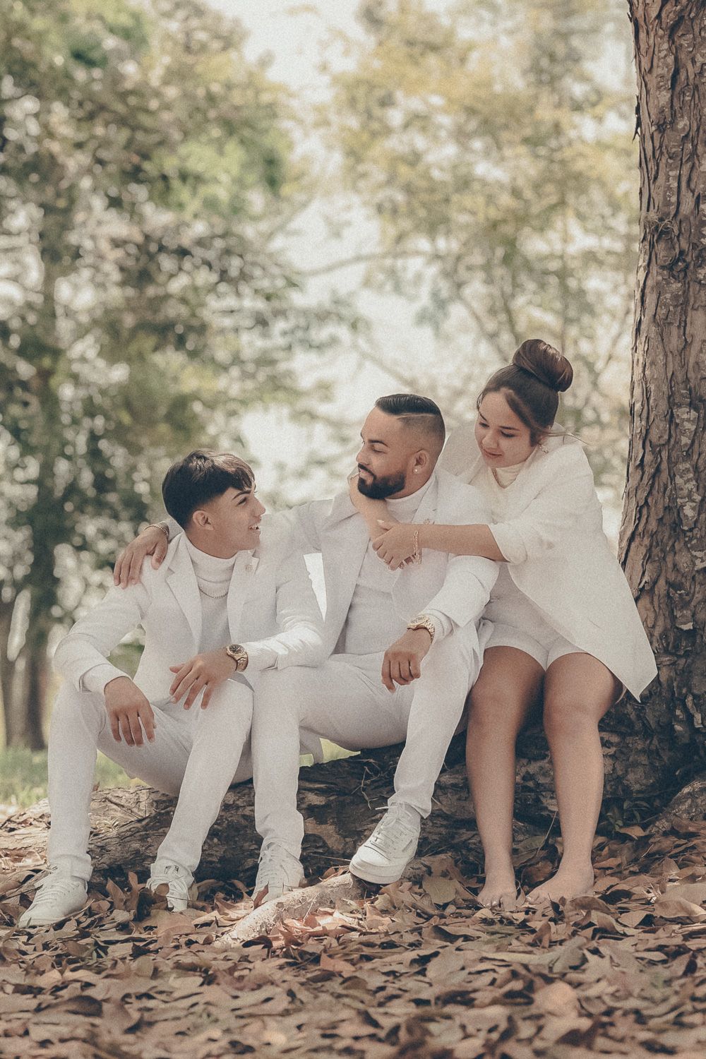Candid family portrait of two parents and their teenage son laughing together beneath a tree outdoors