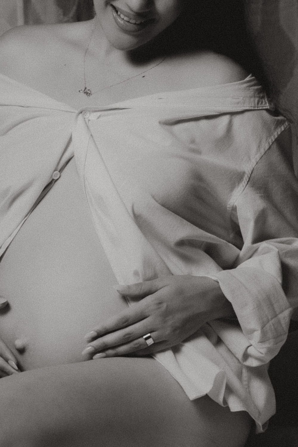 Black and white close-up maternity portrait of an expecting mother holding her baby bump