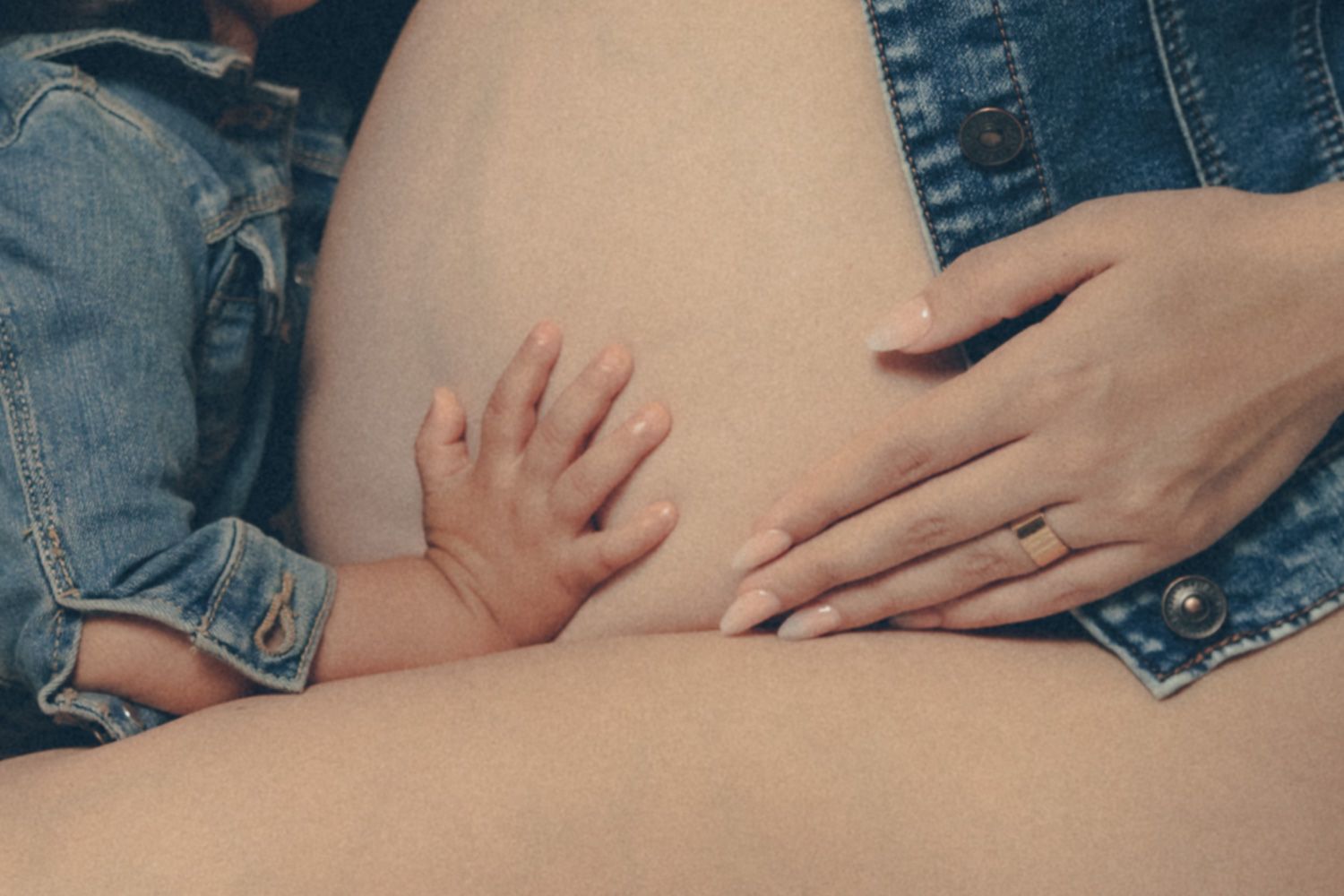 Baby's hand resting on mother's pregnant belly during an intimate maternity portrait