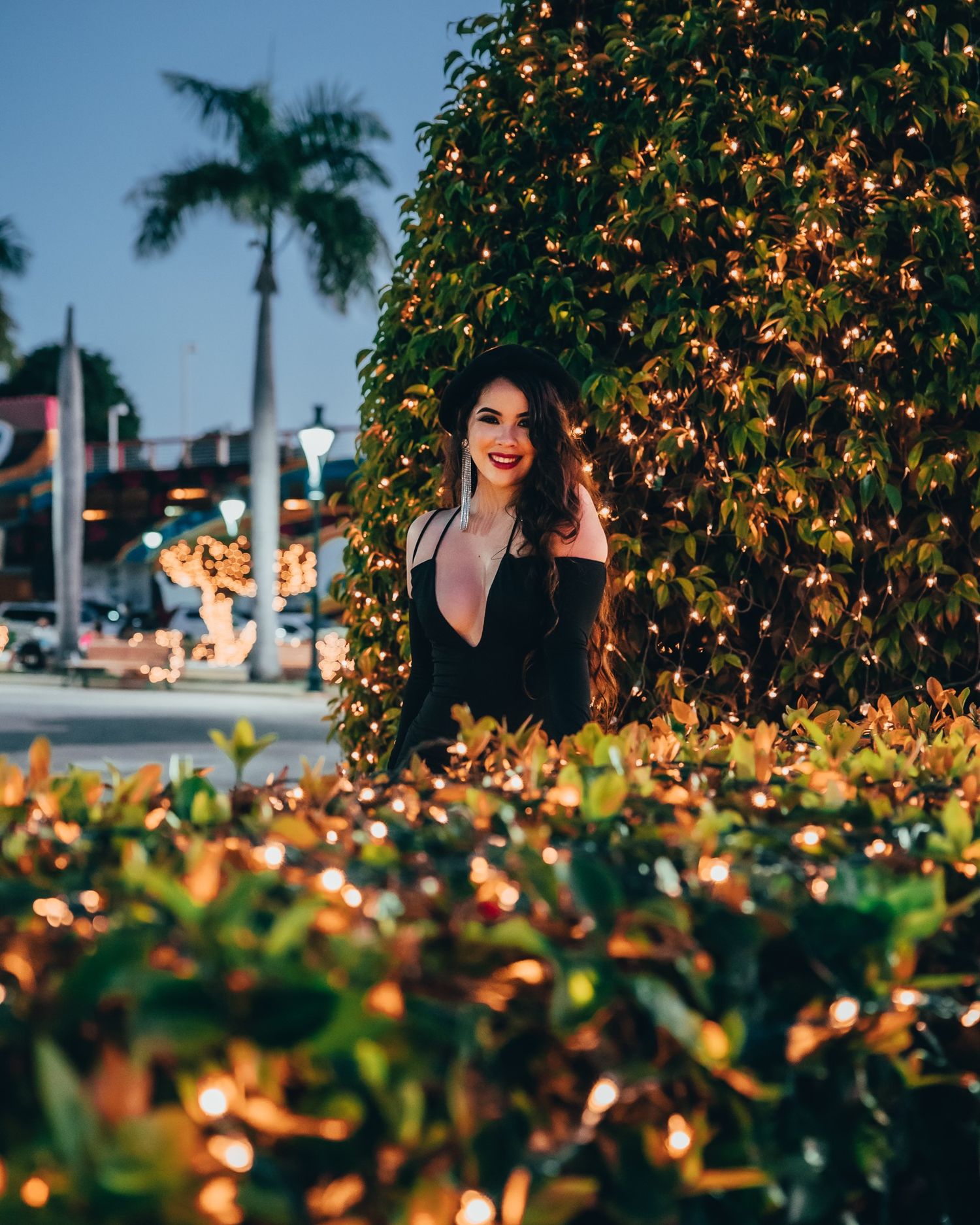 Nighttime fashion portrait of brunette model in a black dress surrounded by decorative lights