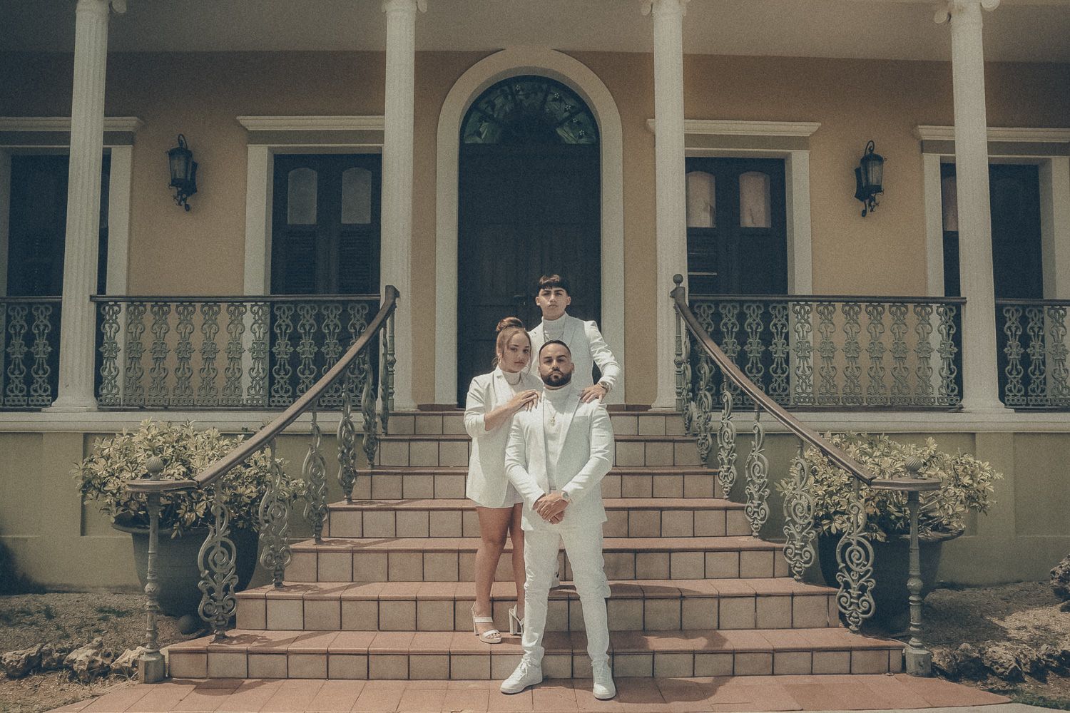 Elegant family portrait of parents and their child dressed in white and posing together on the steps of a historic home