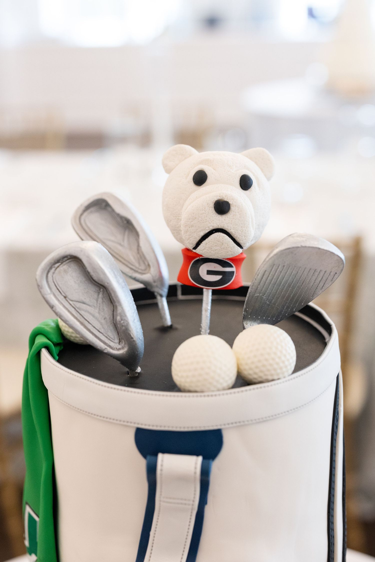 Close-up of golf bag groom's cake featuring UGA bulldog mascot figurine with golf clubs and white balls.