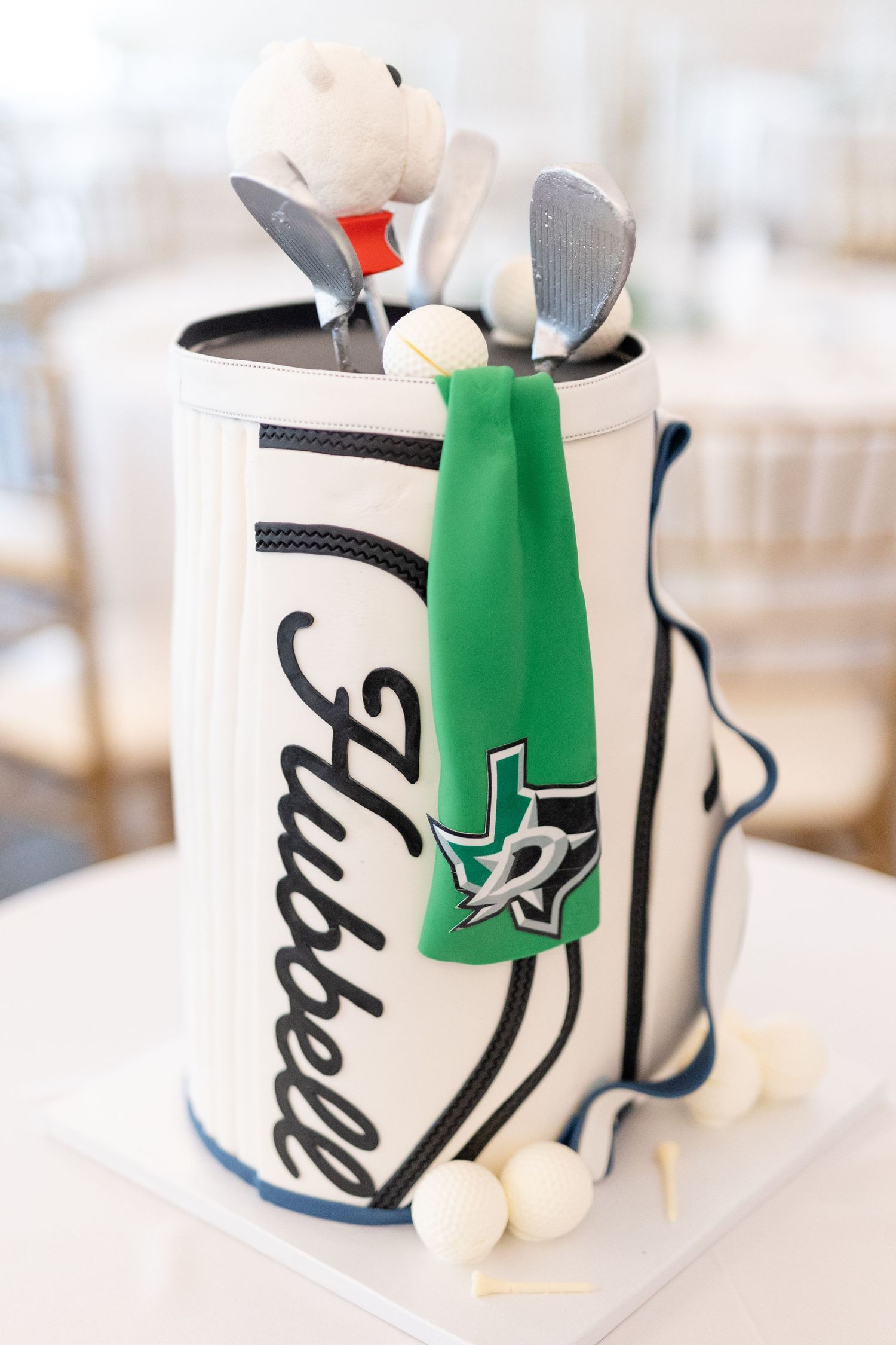 Golf bag groom's cake with Hubbell name, Dallas Stars green towel, UGA bulldog topper, and golf accessories.