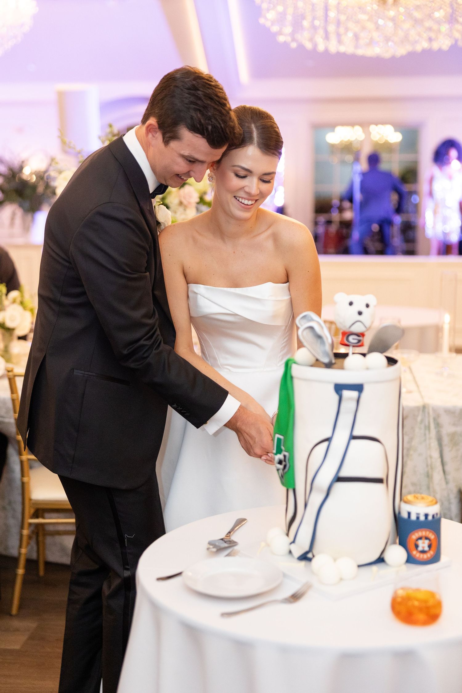 Bride and groom cutting golf bag-shaped grooms cake at elegant wedding reception.